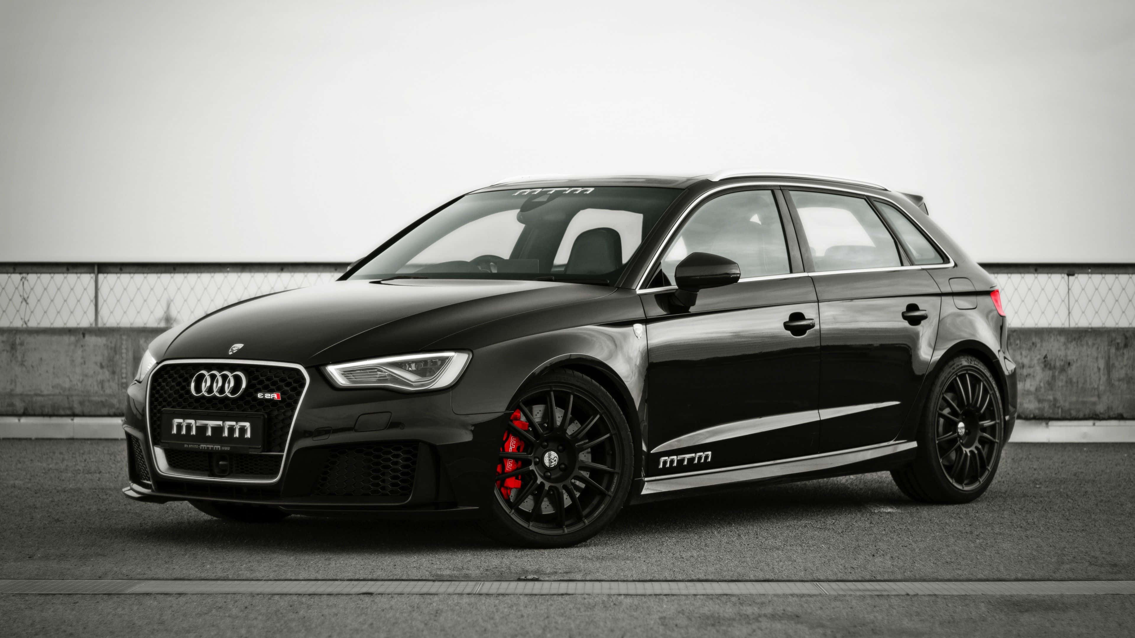 Audi Rs3 桌布 壁紙 — 一架時尚黑色MTM改裝奧迪RS3 Sportback，配備紅色制動卡鉗，停泊在瀝青賽道上。