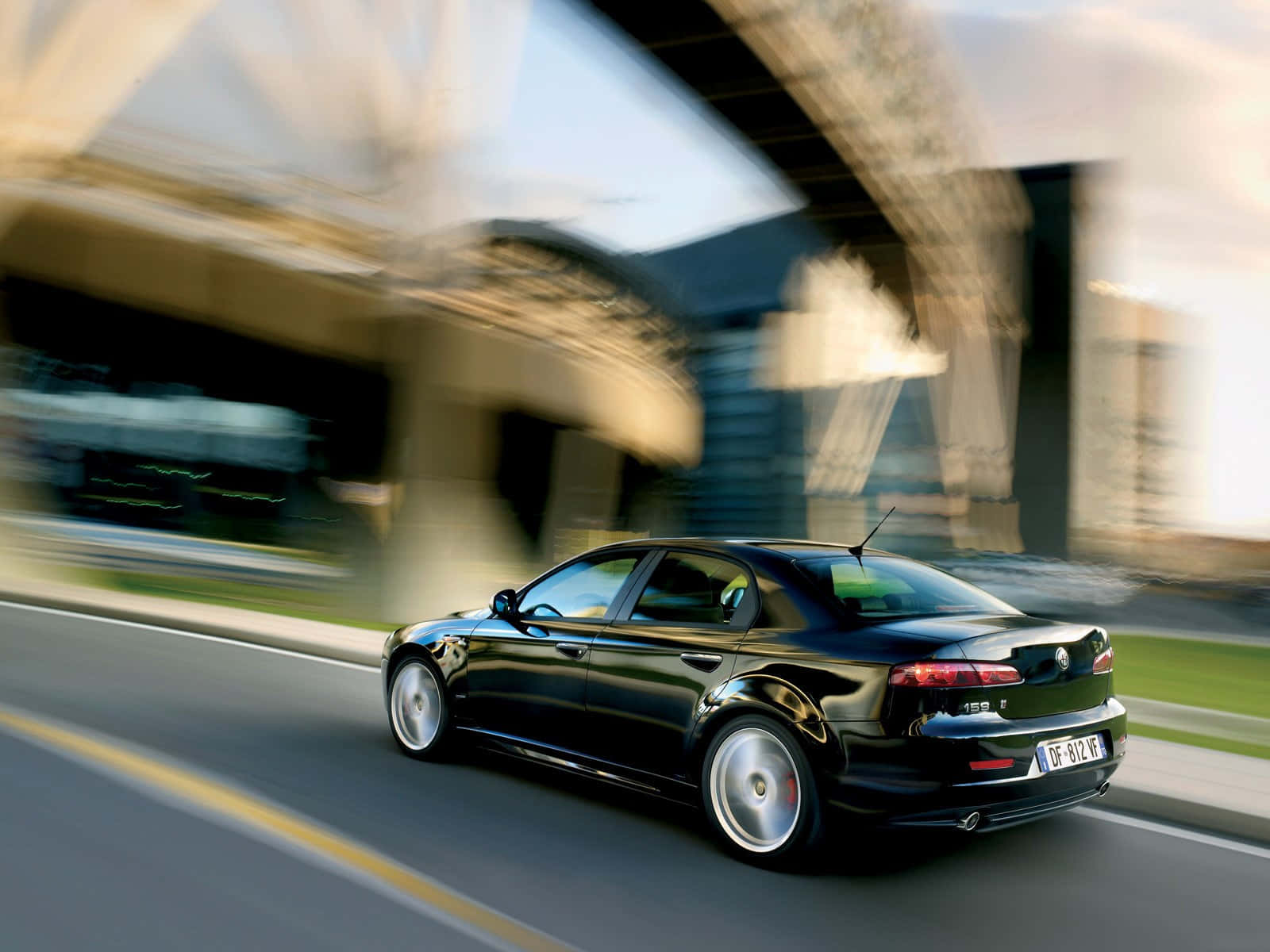 Alfa Romeo 159 桌布 壁紙 — 一架時尚黑色房車在現代橋樑下高速行駛，動態模糊傳達快速移動。