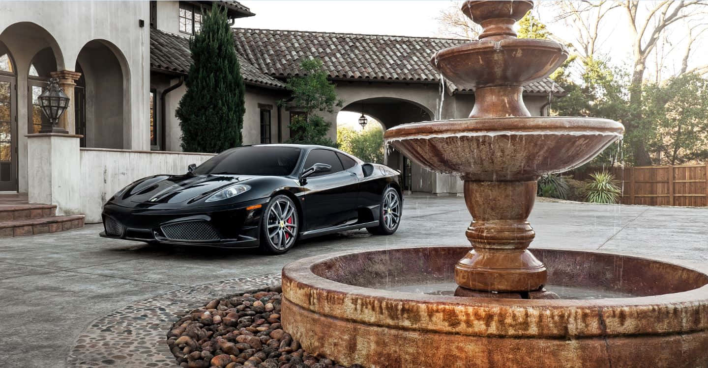 Ferrari Ff 桌布 壁紙 — 一架時尚黑色法拉利跑車停泊在豪華庭院內風化的石噴泉旁。