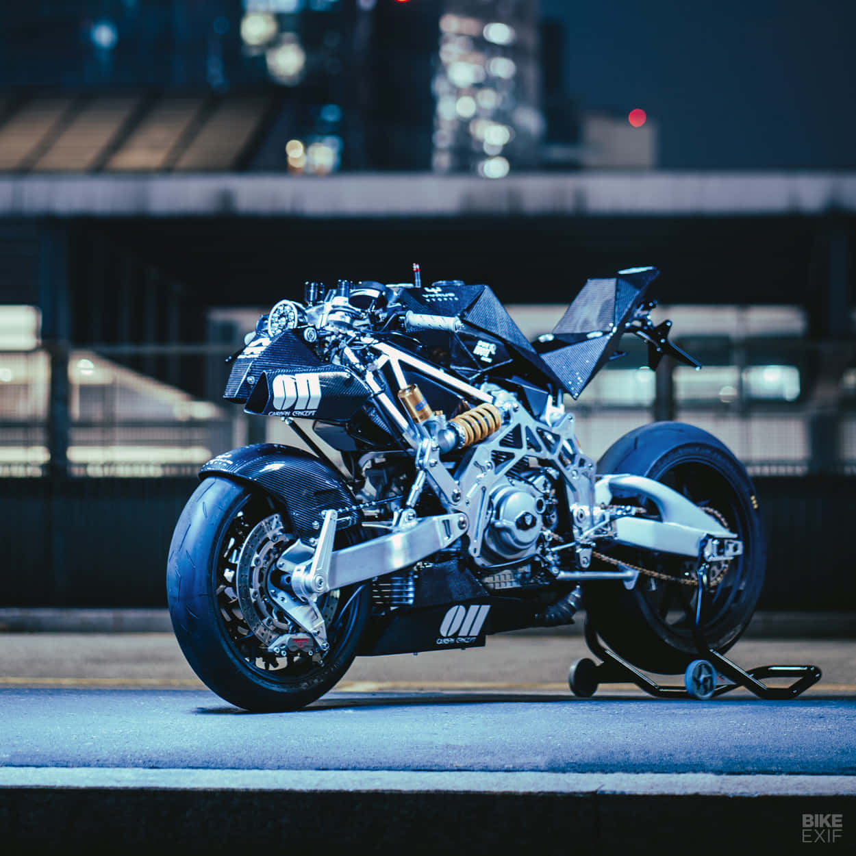 Vyrus Motorcycle 桌布 壁紙 — 一架未來感十足的黑色電單車，暴露著機械細節，在夜晚的城市街道上，處於冷藍色燈光下。