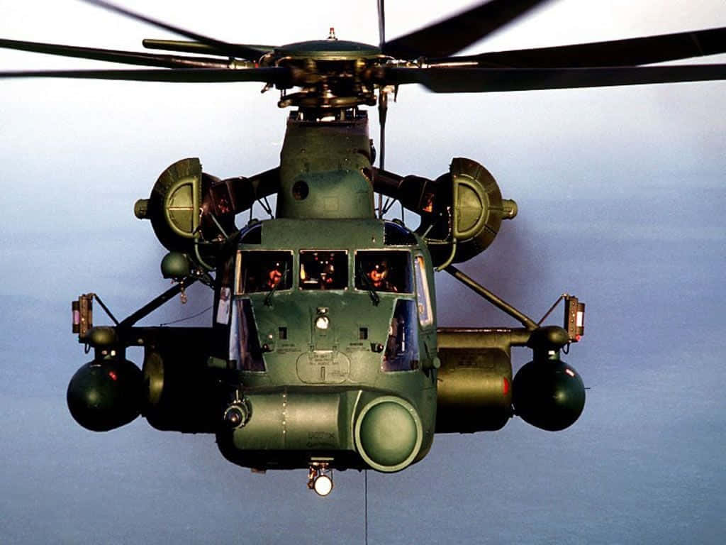 Helicopter 桌布 壁紙 — 一架橄欖綠色的軍用直升機在淡藍色的天空中盤旋，旋翼轉動。