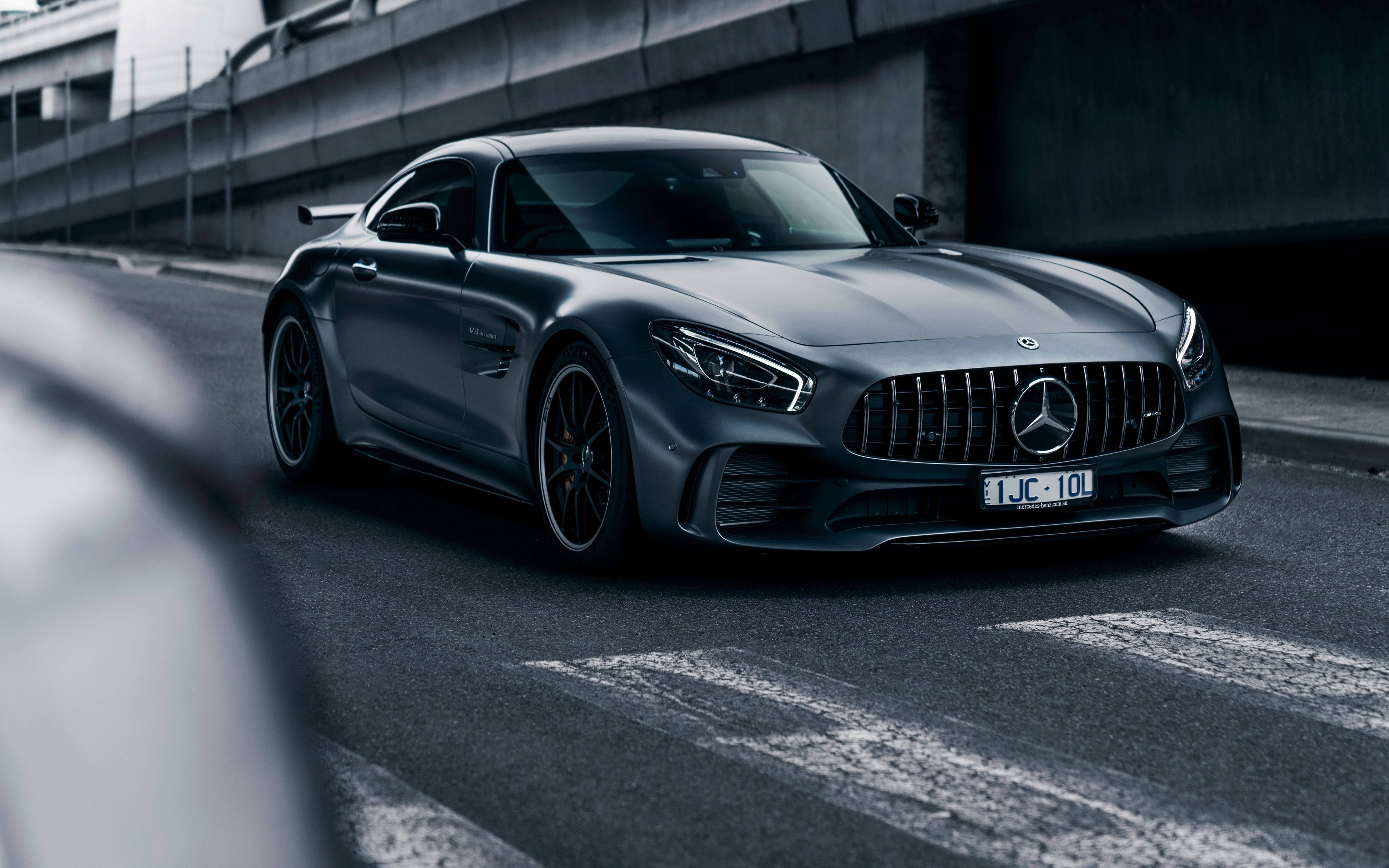 黑色動態圖 桌布 壁紙 — 一架流線型啞光灰色梅賽德斯-AMG GT R跑車停在天橋下的混凝土城市道路上。