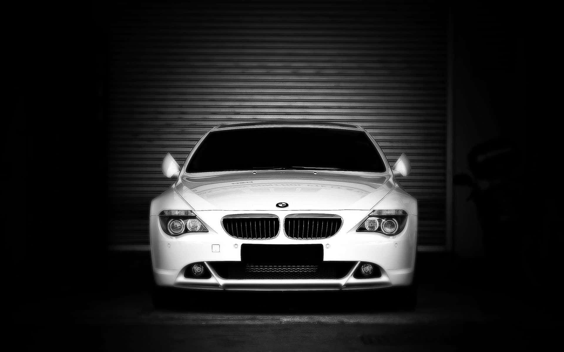 Bmw 6 Series 桌布 壁紙 — 一架流線型白色BMW跑車，在深色車庫門前從下方戲劇性地打光，呈現高對比度的黑白效果。