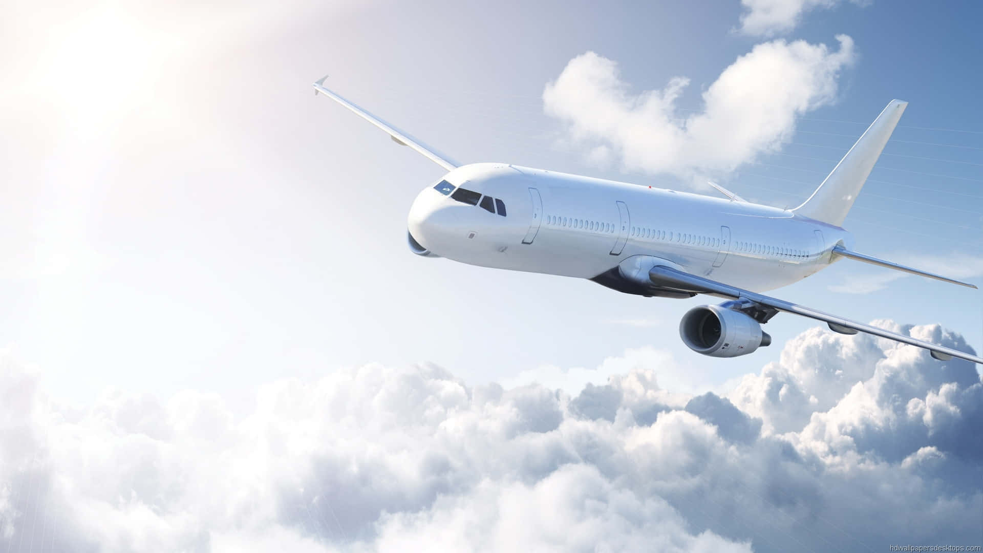 Aviation 桌布 壁紙 — 一架流線型白色客機在明亮的藍天下優雅地翱翔於蓬鬆的白雲之上。