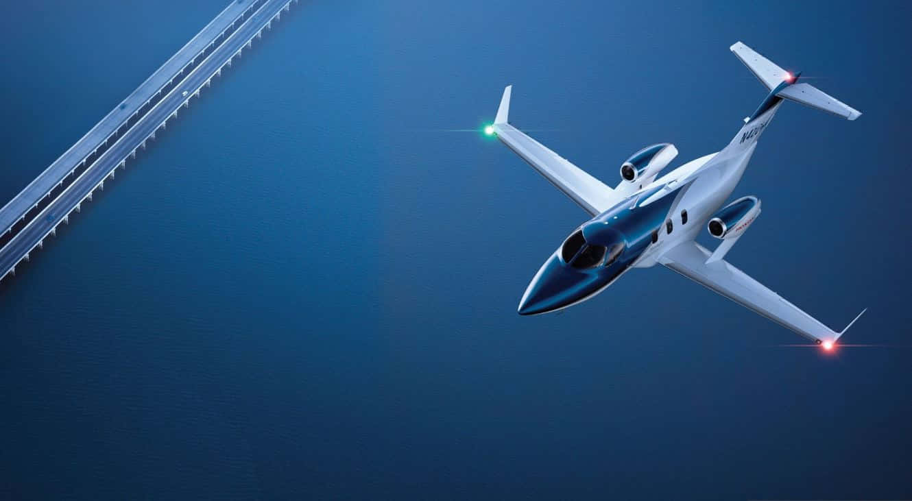 Flight 桌布 壁紙 — 一架流線型白色私人飛機低飛過深藍色水面，遠處有一座長橋延伸開去。