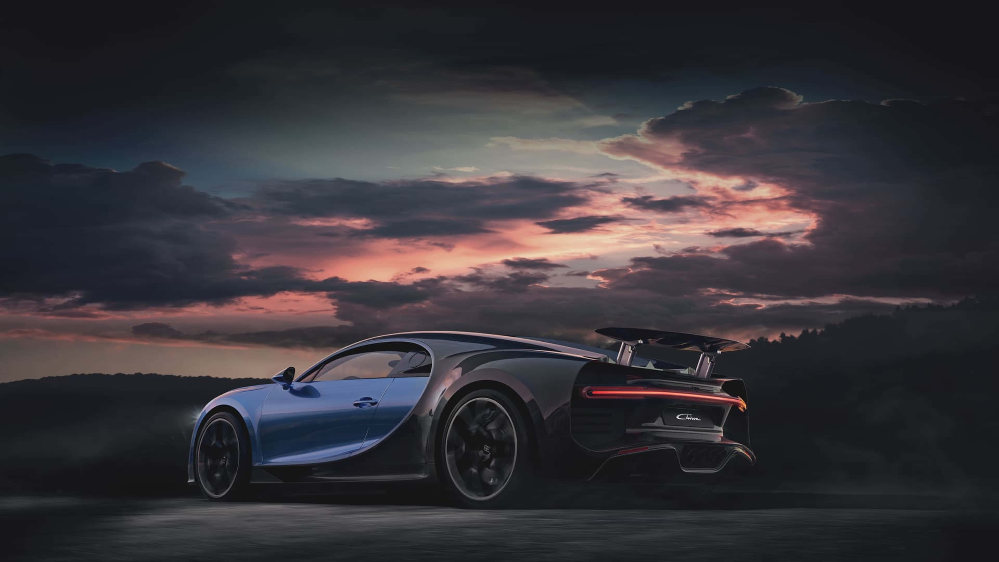 4K Car 桌布 壁紙 — 一架流線型的藍色Bugatti Chiron跑車在昏暗的道路上行駛，天空呈現戲劇性的暮色，帶有粉紅色和紫色的雲彩。