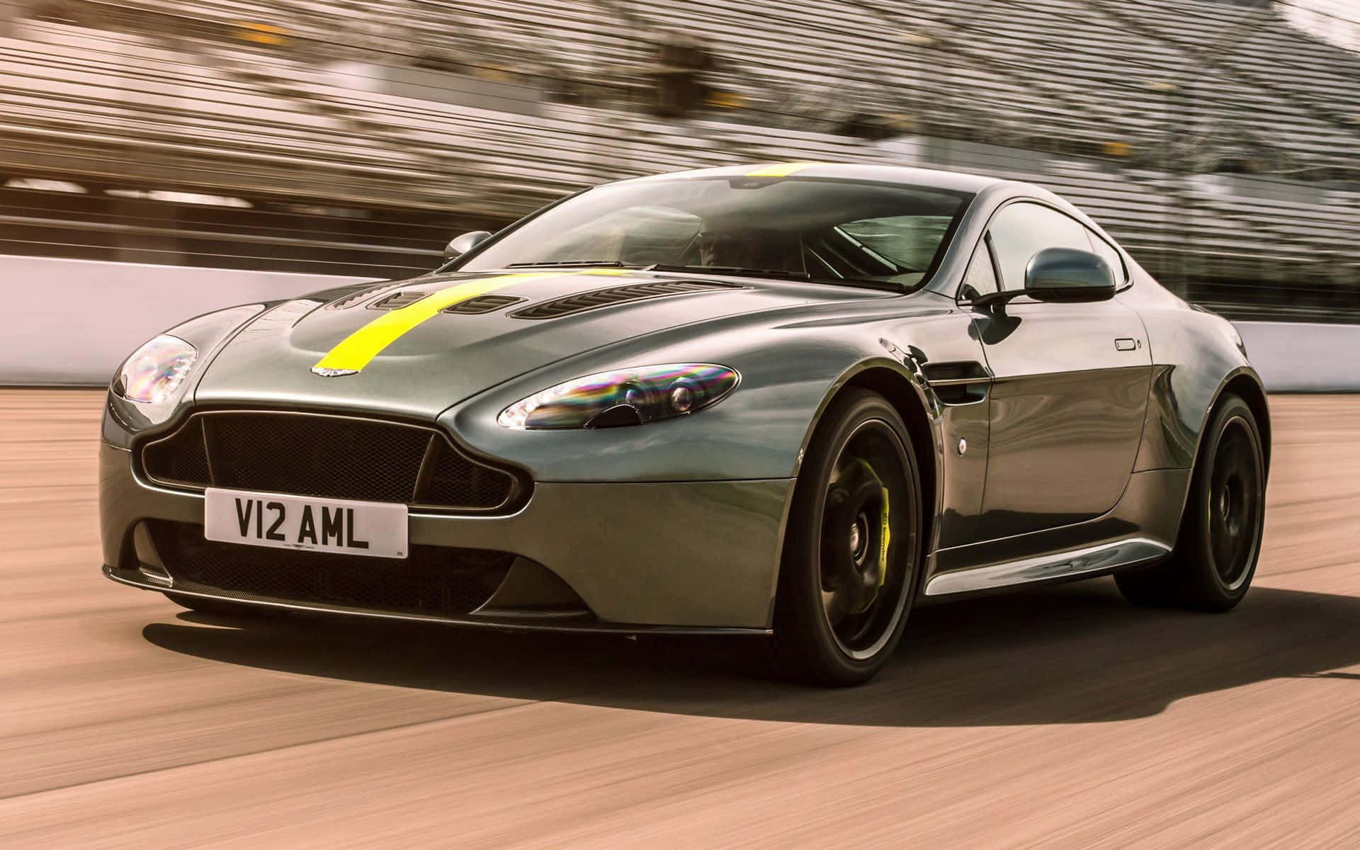 Aston Martin V12 Vantage 桌布 壁紙 — 一架流線型的銀色 Aston Martin V12 AMR 在賽道上飛馳，背景是模糊的看台。