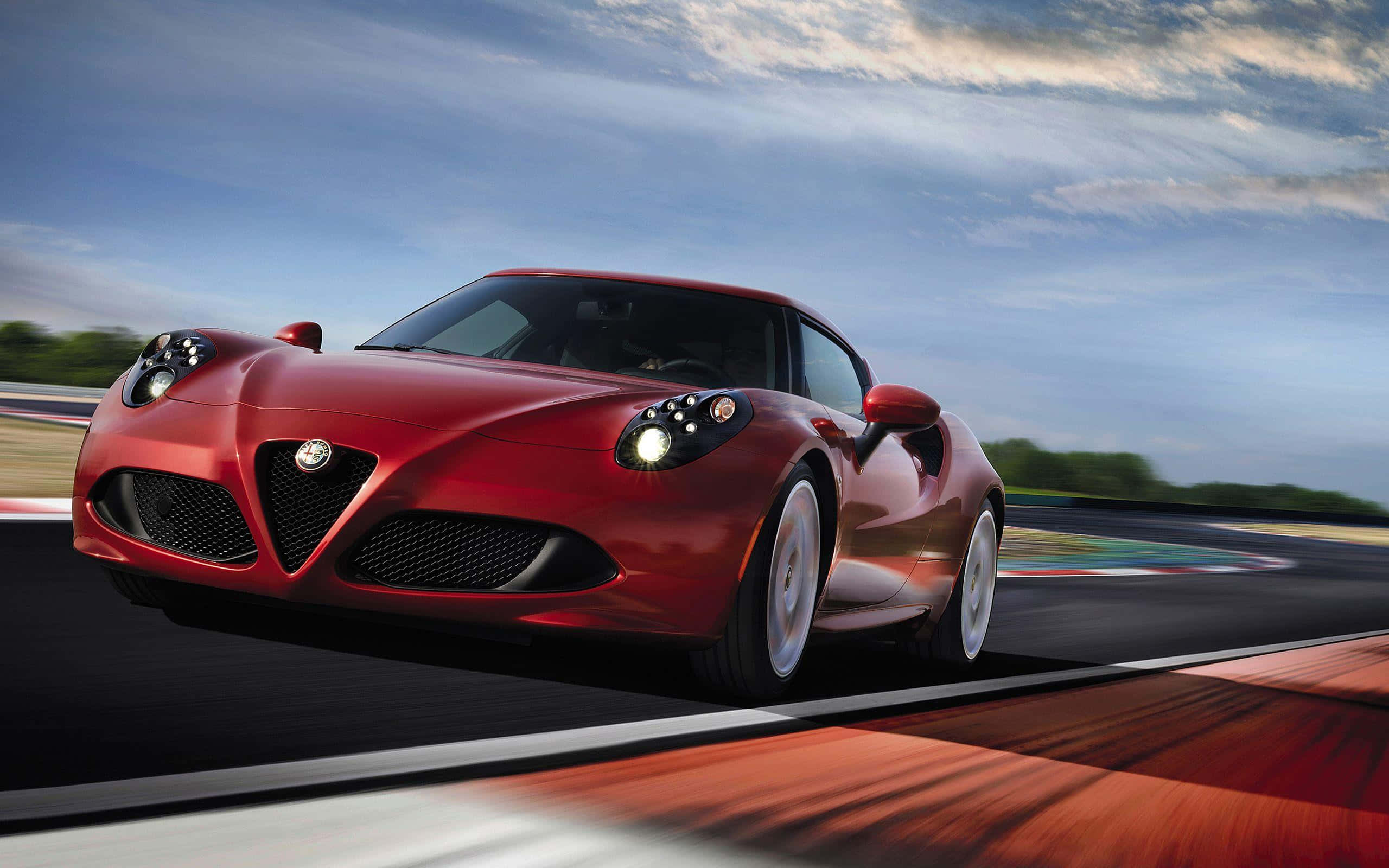Alfa Romeo 4c 桌布 壁紙 — 一架流線型紅色愛快羅密歐跑車在動感天空下，伴隨動態模糊效果，沿賽道疾馳。