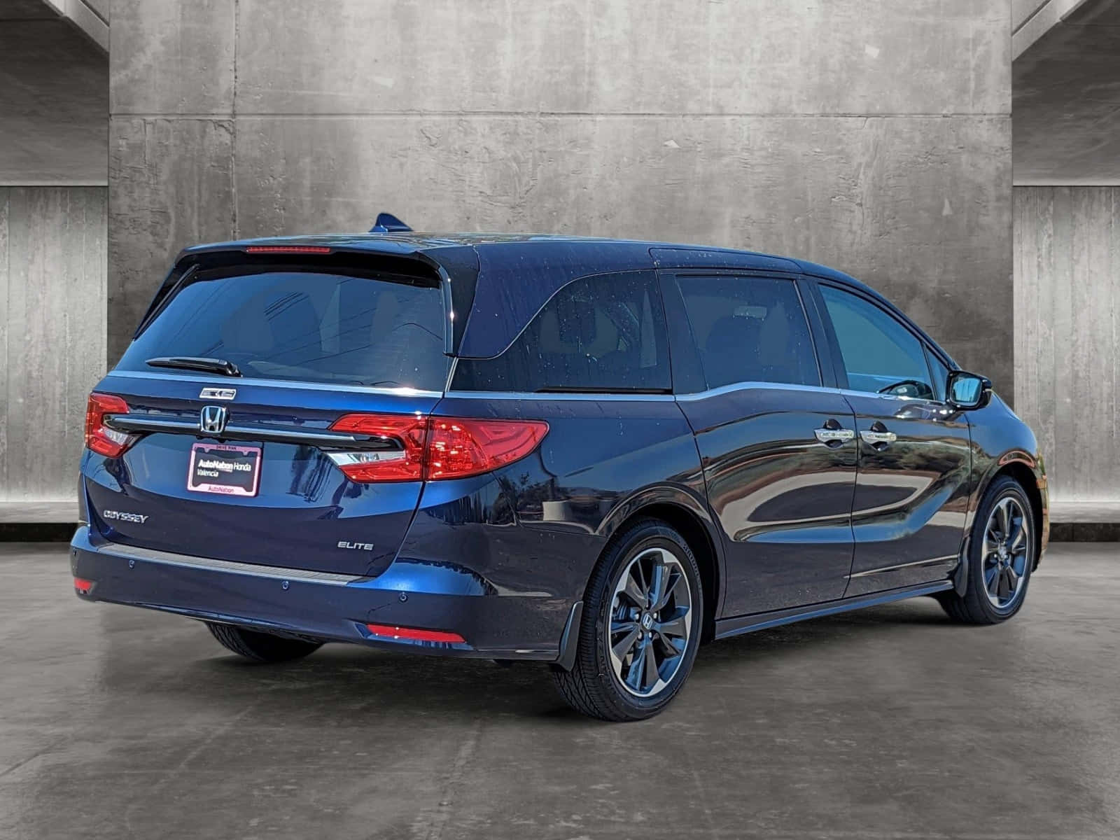 Honda Odyssey 桌布 壁紙 — 一架流線型藍色本田 Odyssey Elite 小型貨車停泊在帶有反射表面的紋理混凝土牆旁。
