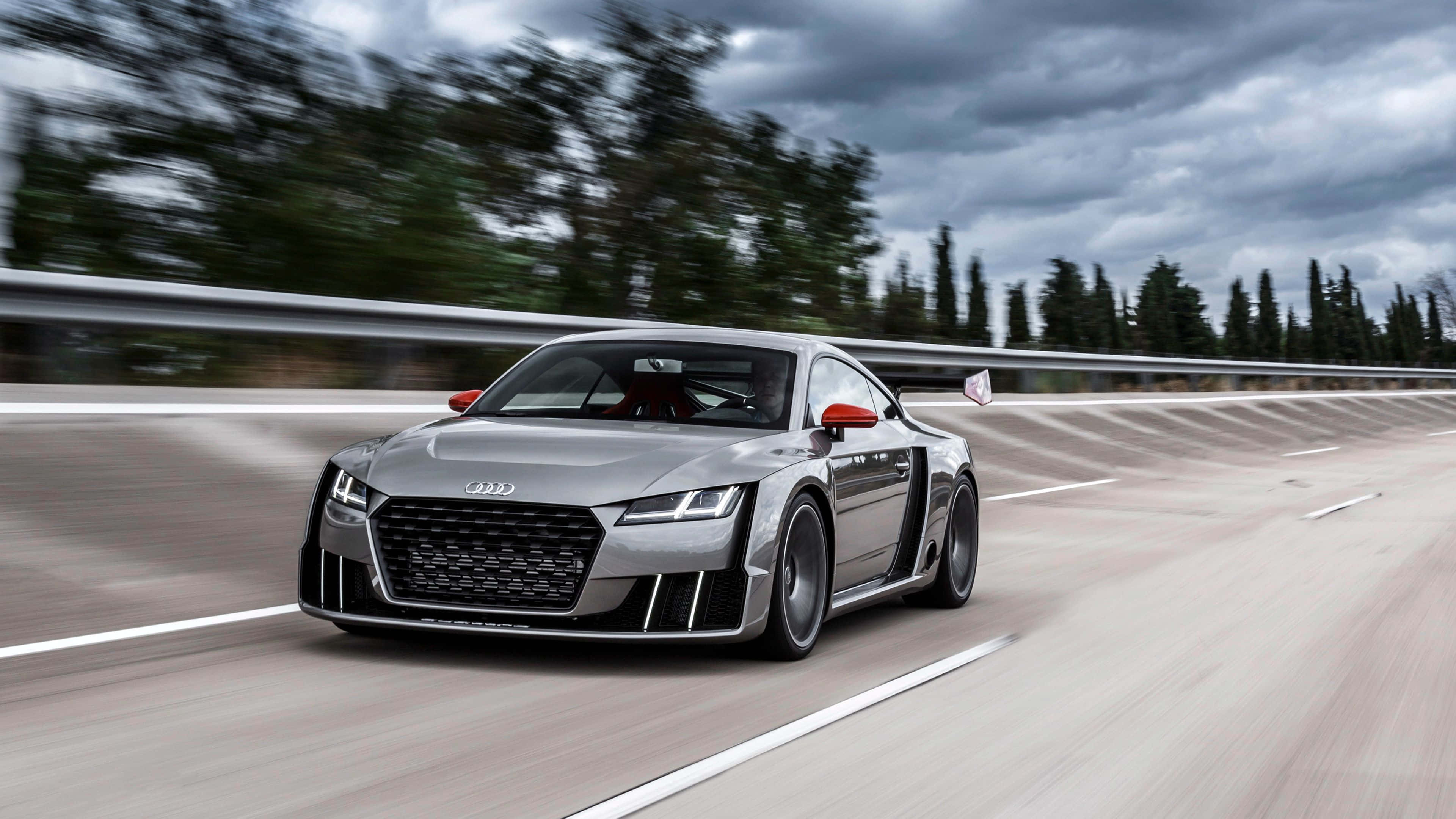 Audi Tt 桌布 壁紙 — 一架流線型銀色奧迪R8在蜿蜒的高速公路上飛馳，背景是模糊的樹木和陰天。
