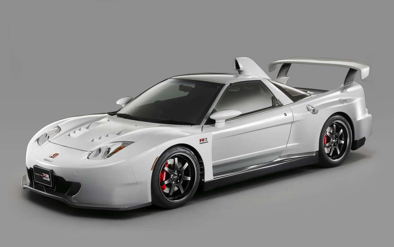 Honda Nsx 桌布 壁紙 — 一架流線型銀色跑車，配備大型尾翼和紅色制動卡鉗，在灰色中性攝影棚背景下擺拍。