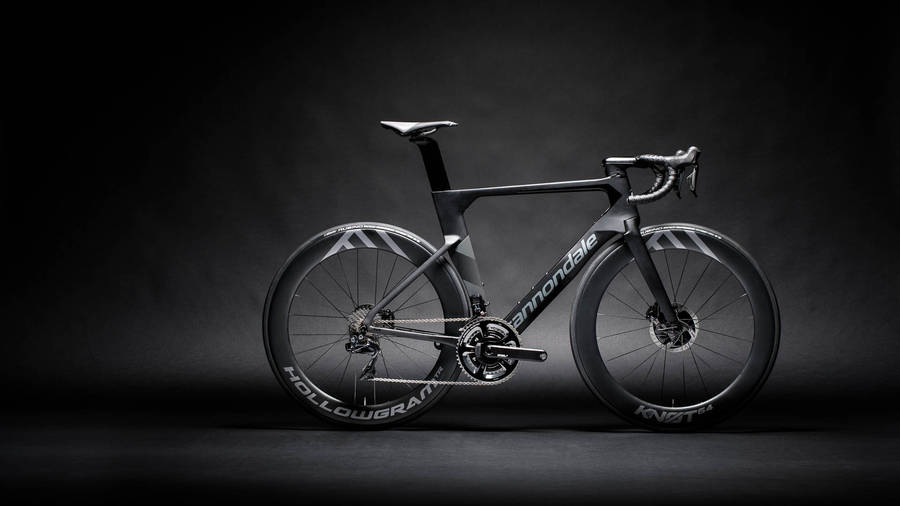 桌布 壁紙 — 一架流線型黑色Cannondale公路單車配備深截面車輪，在黑暗的攝影棚背景下戲劇性地照亮。