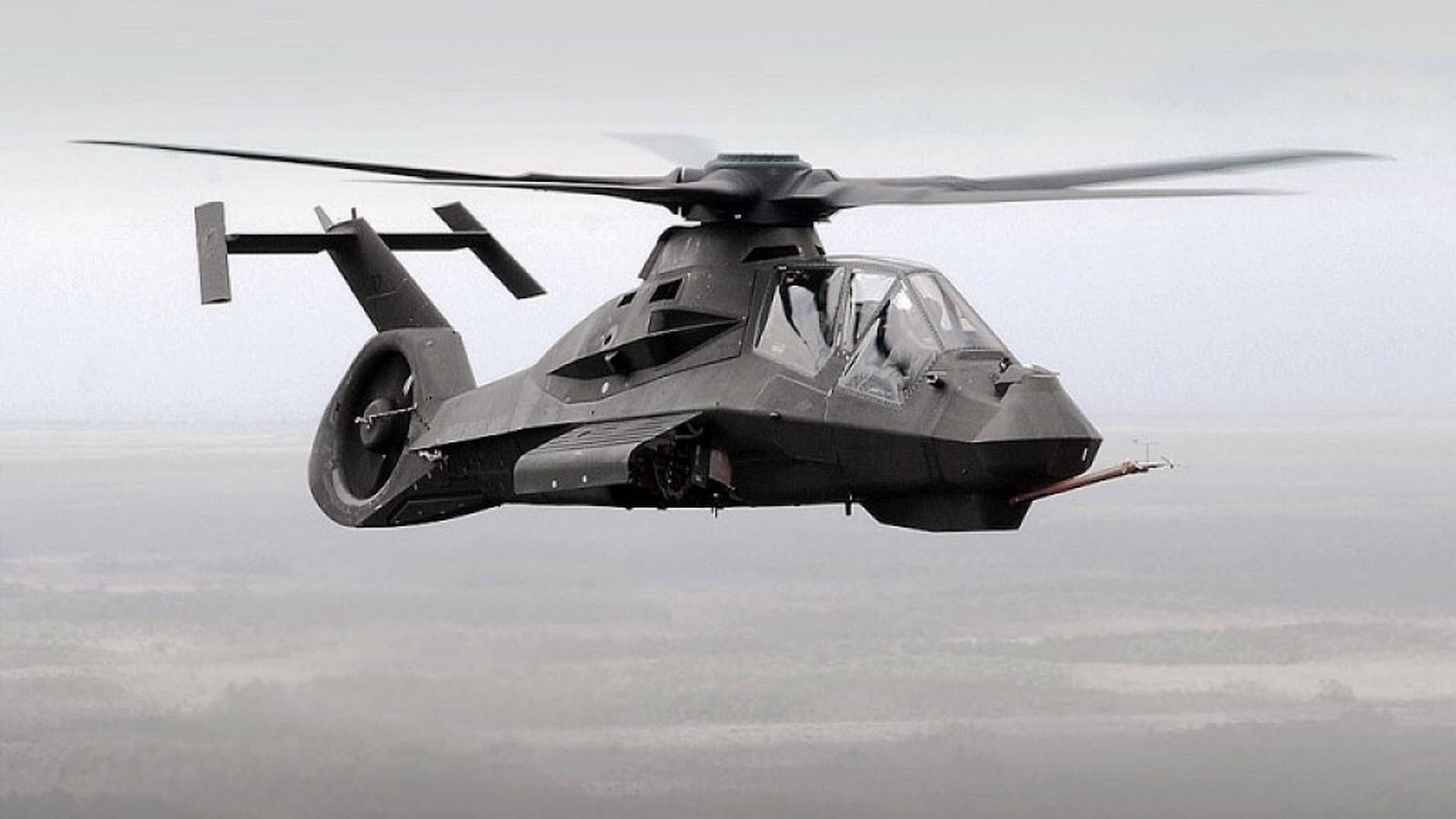 Comanche Canceled Military Helicopter 壁紙 — 一架流線型黑色隱形直升機低空盤旋於霧氣瀰漫、地形模糊的景觀之上。