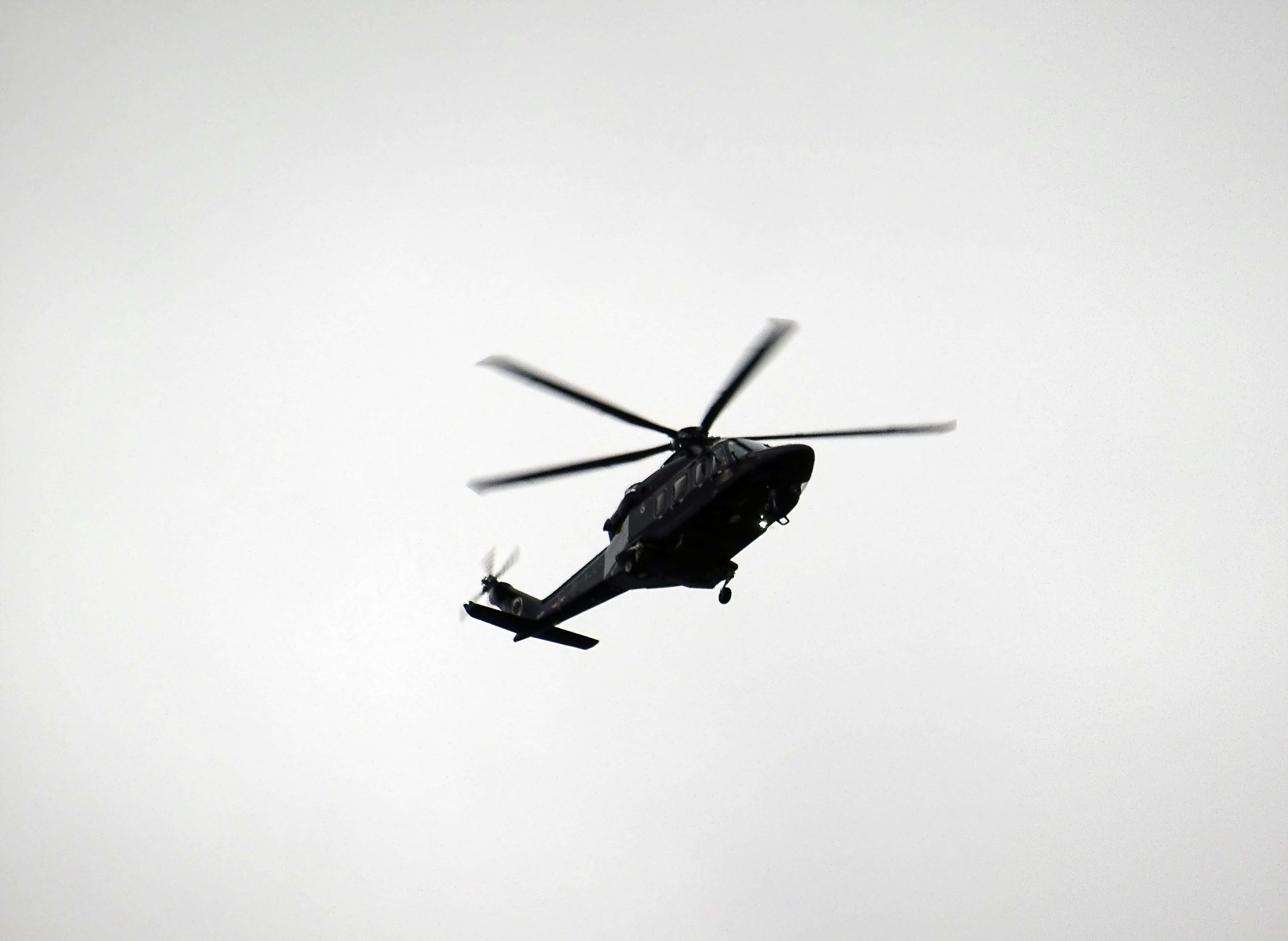Helicopter 桌布 壁紙 — 一架深色直升機在蒼白多雲的天空中飛行，旋翼旋轉形成剪影。