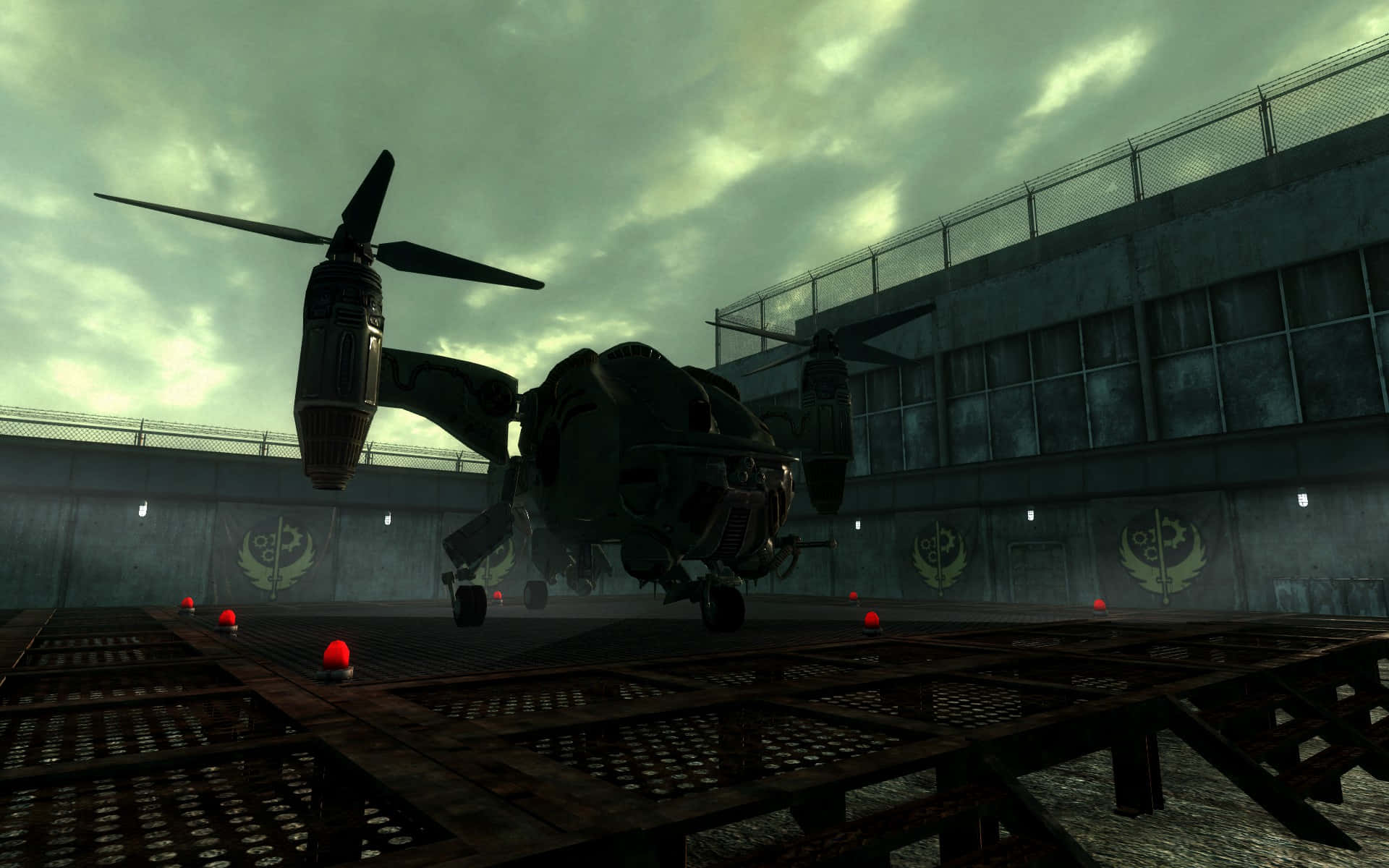 Fallout 4 The Capital Wasteland 桌布 壁紙 — 一架深色軍用直升機在陰沉工業區的鏽蝕金屬平台上空盤旋，天空多雲。