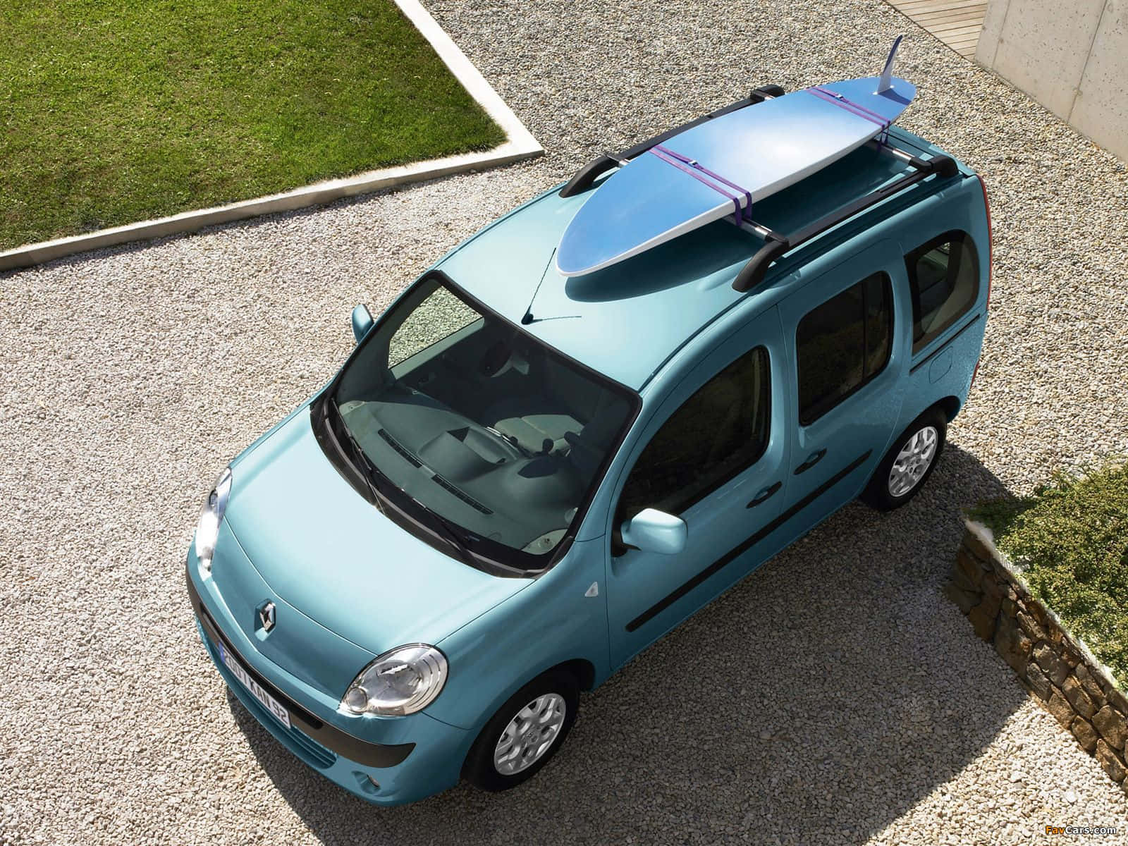 Renault Kangoo 桌布 壁紙 — 一架淺藍色小型客貨車，車頂行李架上綁著一塊衝浪板，停在碎石車道上，旁邊是綠草。