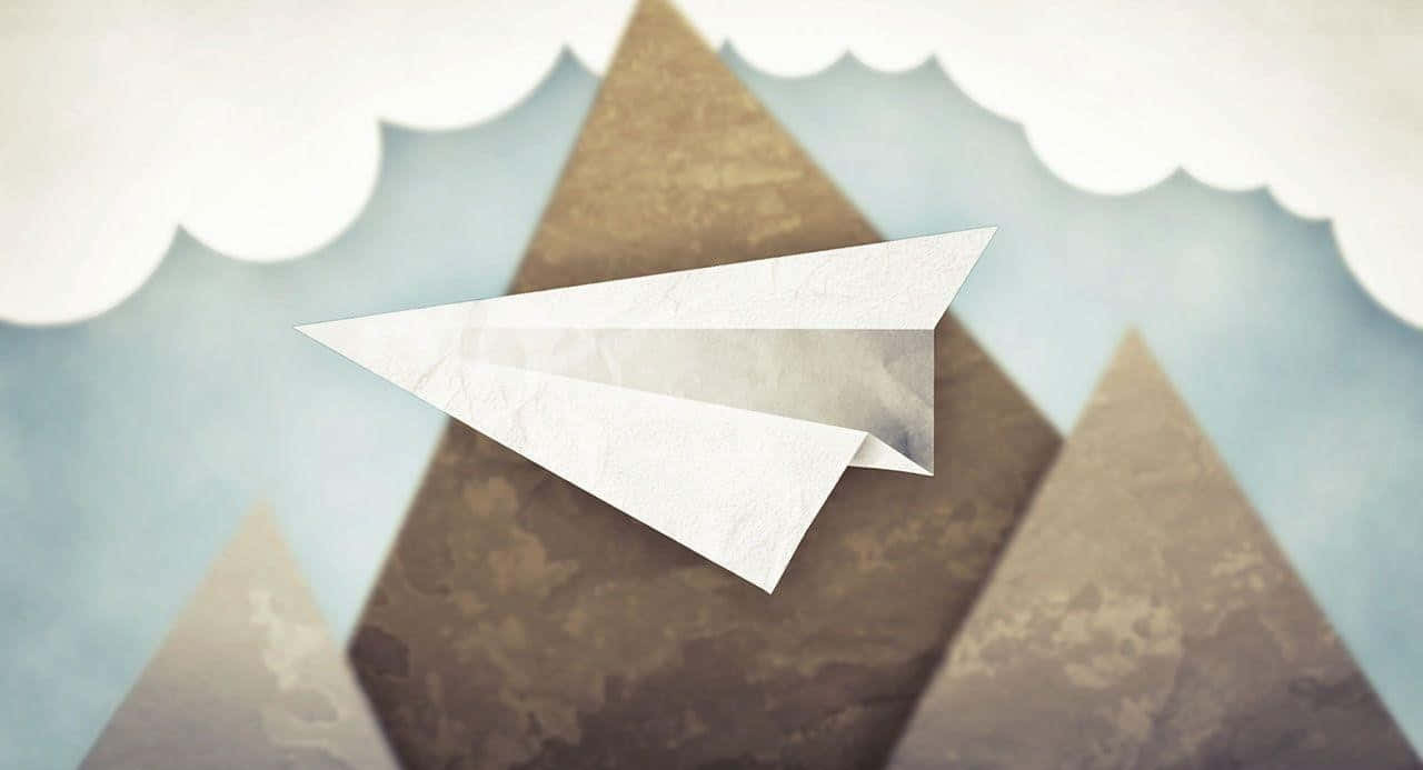 Email 桌布 壁紙 — 一架清晰的白色紙飛機在風格化的棕色山脈上方翱翔，背景是柔和的藍天和蓬鬆的白雲。