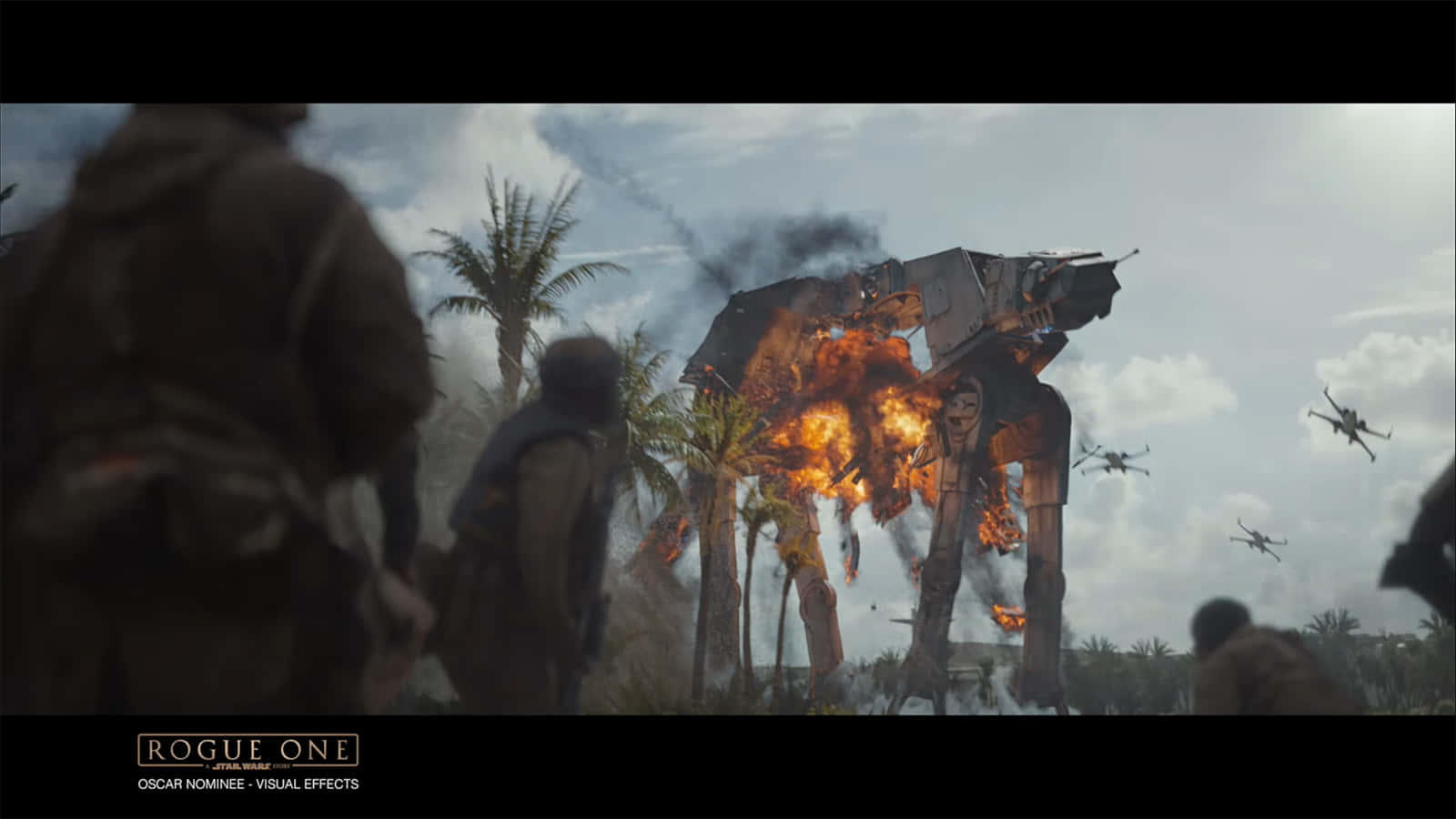 Scarif 桌布 壁紙 — 一架燃燒的AT-AT步行機在熱帶叢林中倒塌，叛軍觀看，戰機在頭頂飛過。