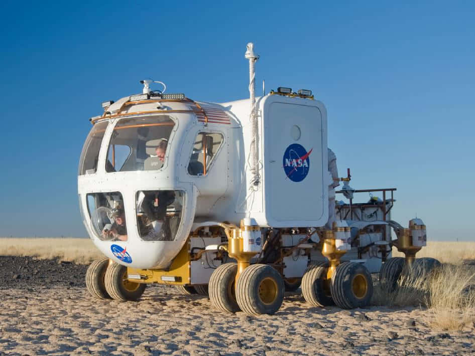 Lunar Rover 桌布 壁紙 — 一架白色NASA月球車，黃色車輪，停泊在晴朗藍天下廣闊的沙漠中。