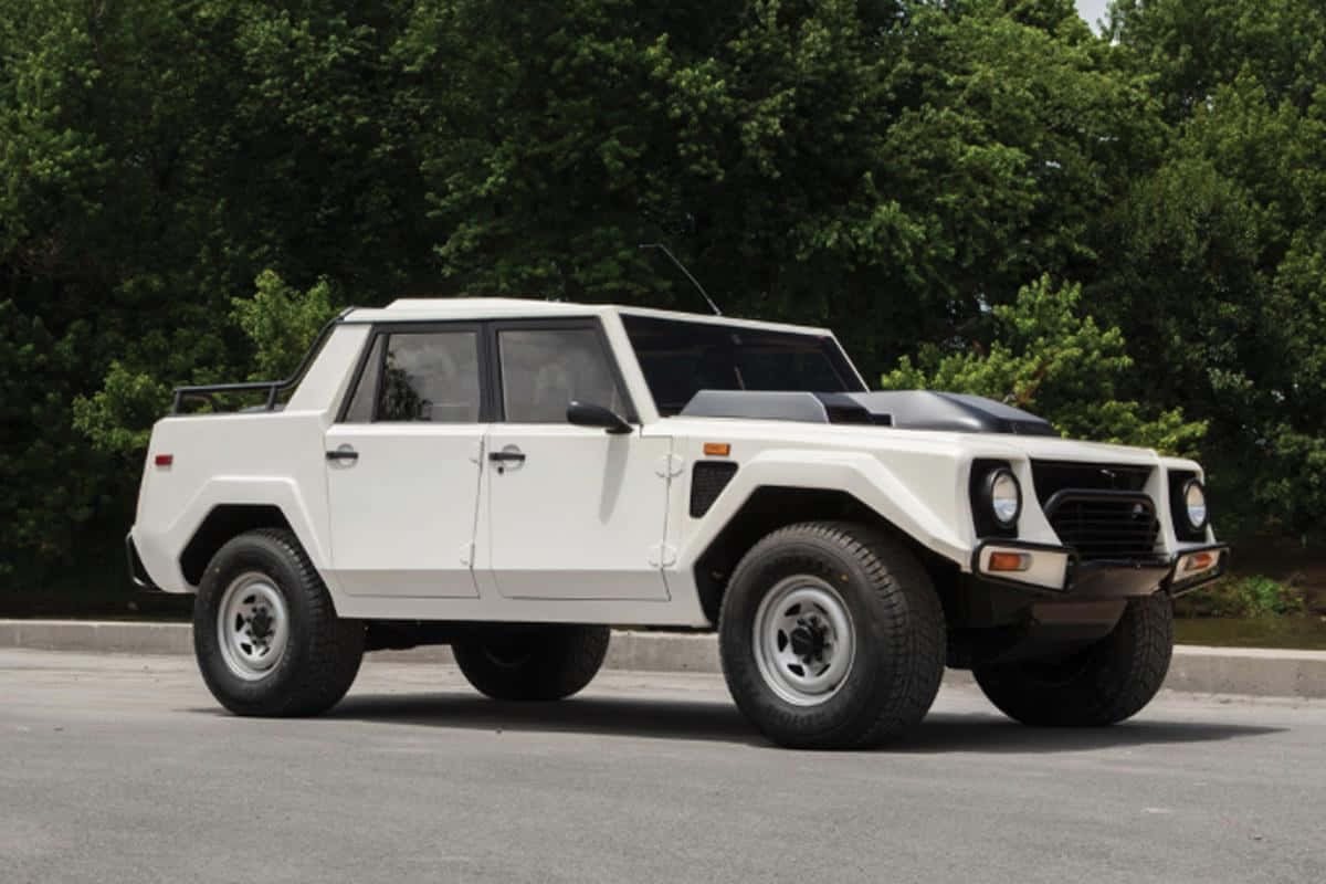 Lamborghini Lm002 桌布 壁紙 — 一架白色林寶堅尼LM002裝甲SUV停泊在瀝青路上，背景有茂密的綠樹。