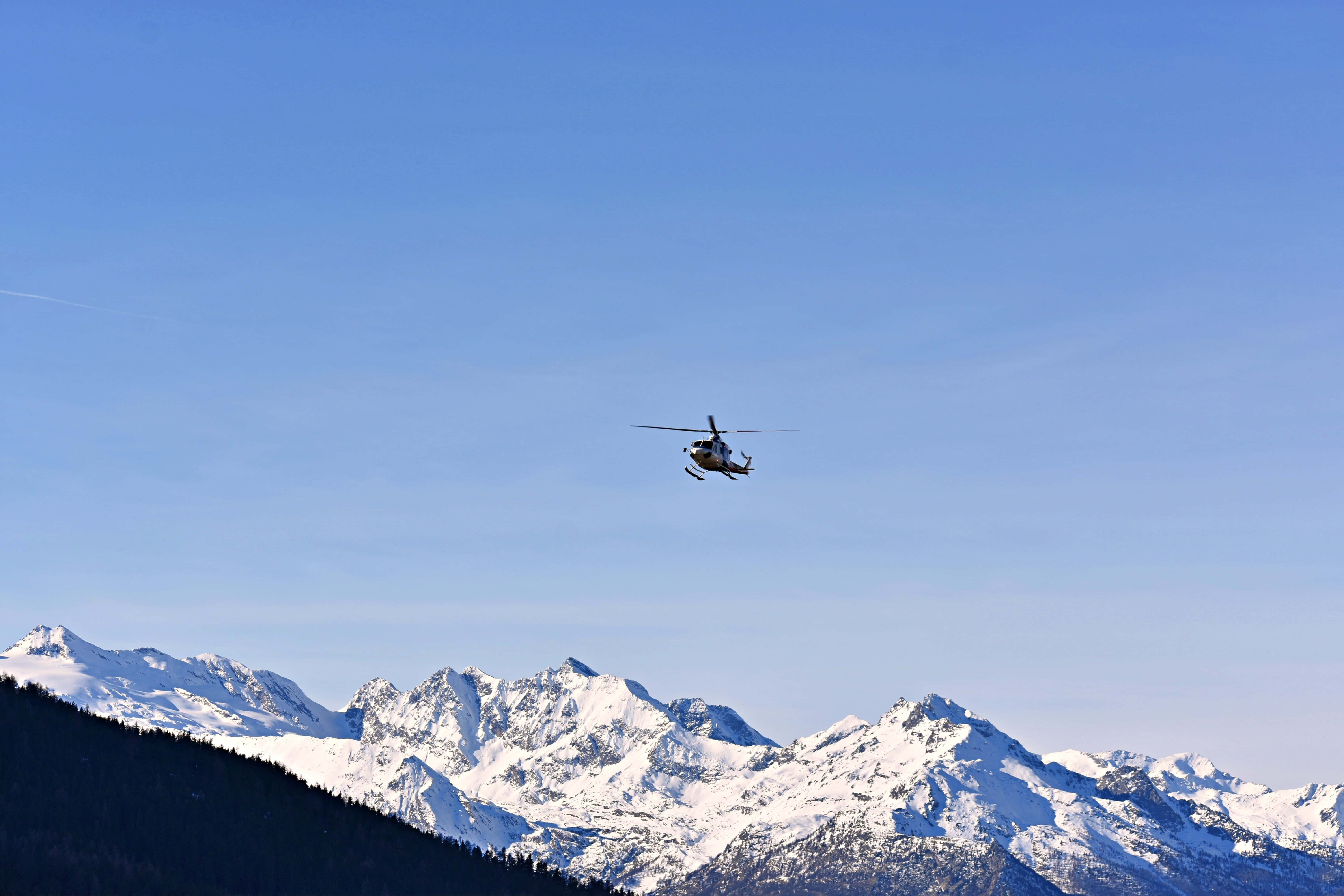 Helicopter 桌布 壁紙 — 一架直升機在晴朗的藍天下翱翔於白雪覆蓋的山峰之上。