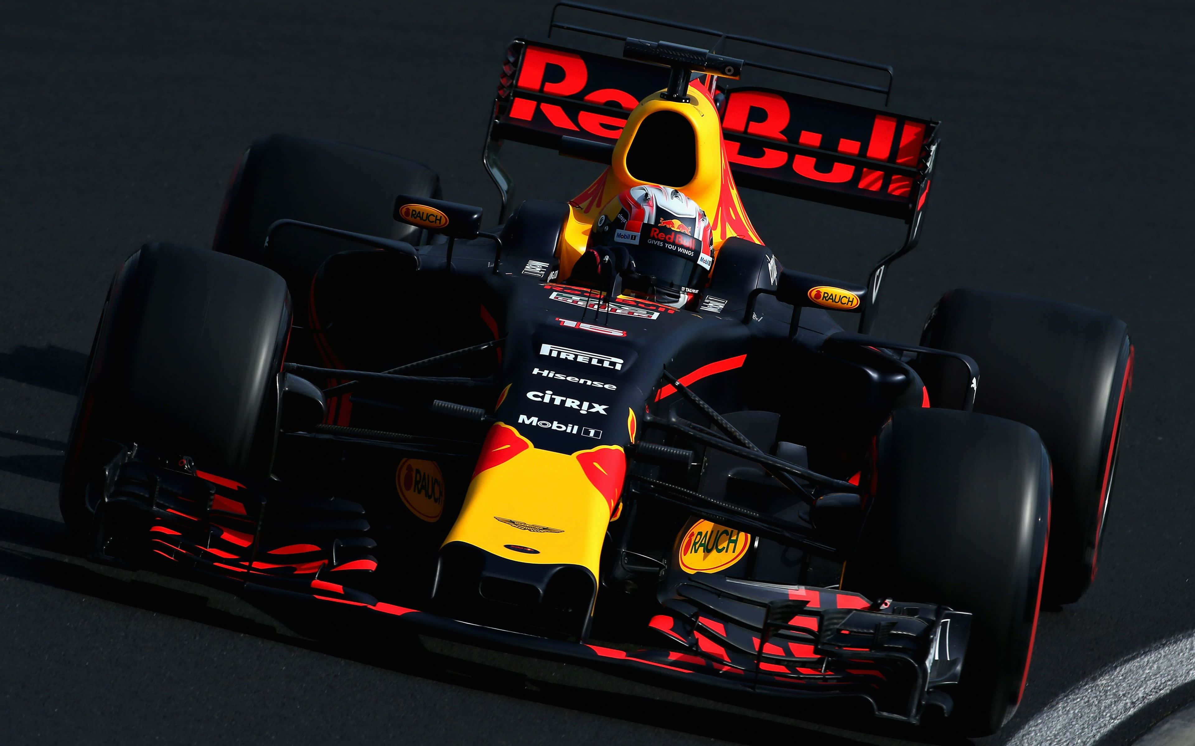 Max Verstappen 桌布 壁紙 — 一架紅牛一級方程式賽車在明亮的陽光下，沿著深色瀝青賽道飛馳，投下清晰的陰影。