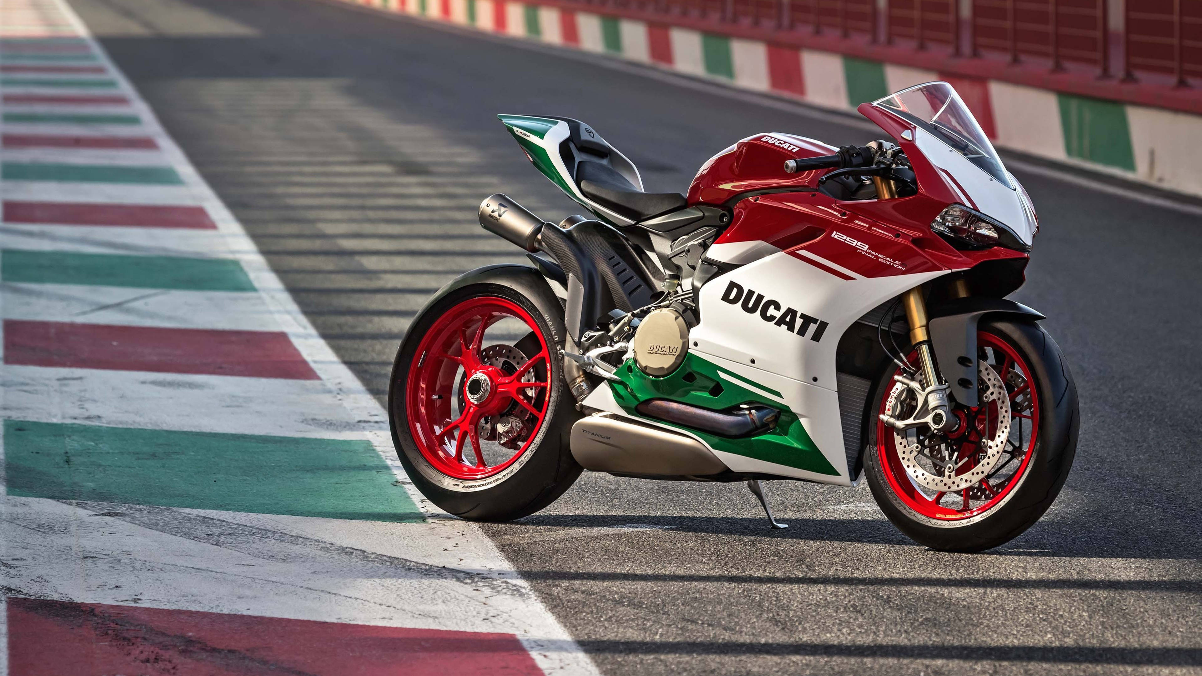 1920X1080 桌布 壁紙 — 一架紅白綠色的Ducati電單車停泊在帶有意大利國旗顏色路緣的賽車場上。