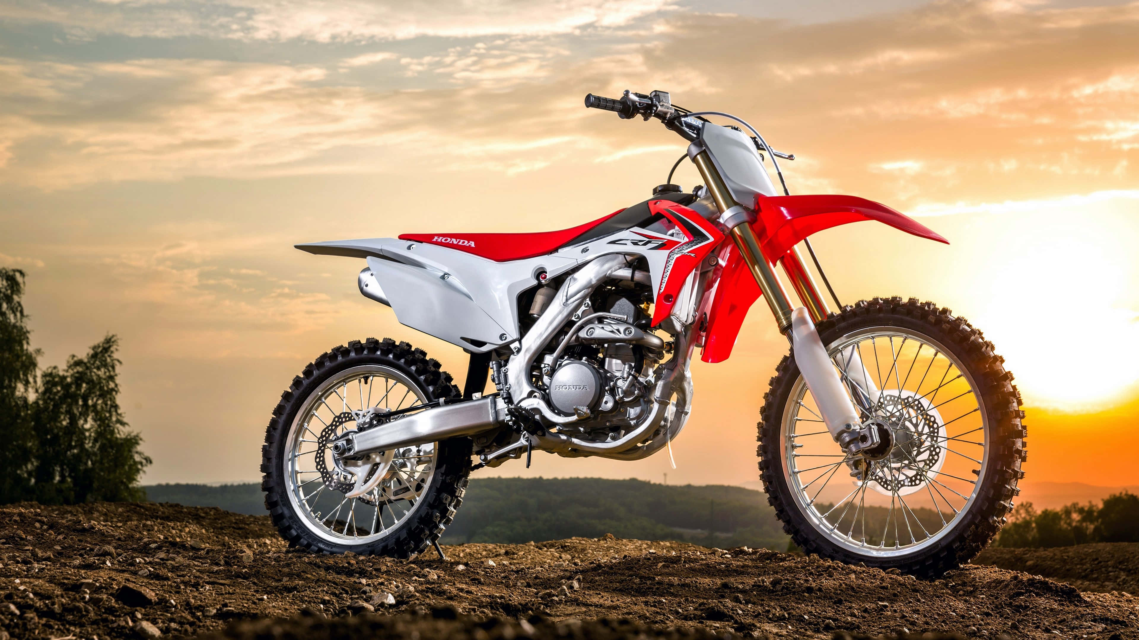 Motocross 桌布 壁紙 — 一架紅白色本田越野電單車在崎嶇地形上，襯著金黃色的日落天空。