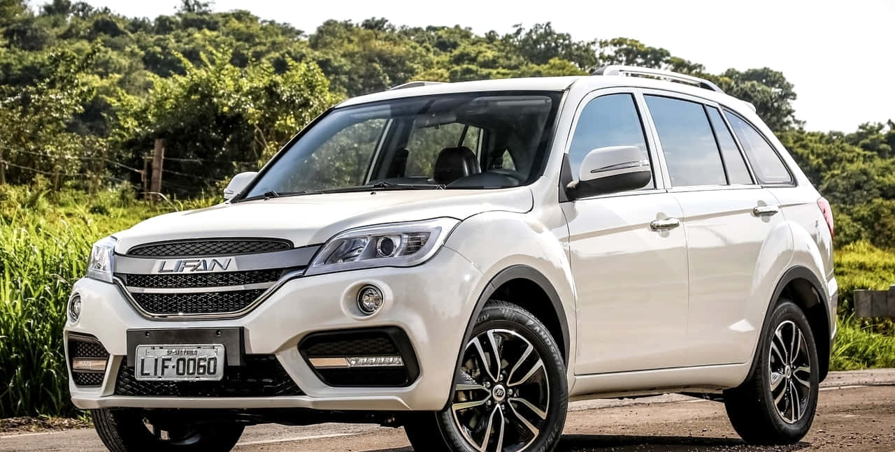 Lifan 桌布 壁紙 — 一架純白色力帆SUV停泊在鄉村道路上，背景是茂密的綠色樹葉，在明亮的日光下。