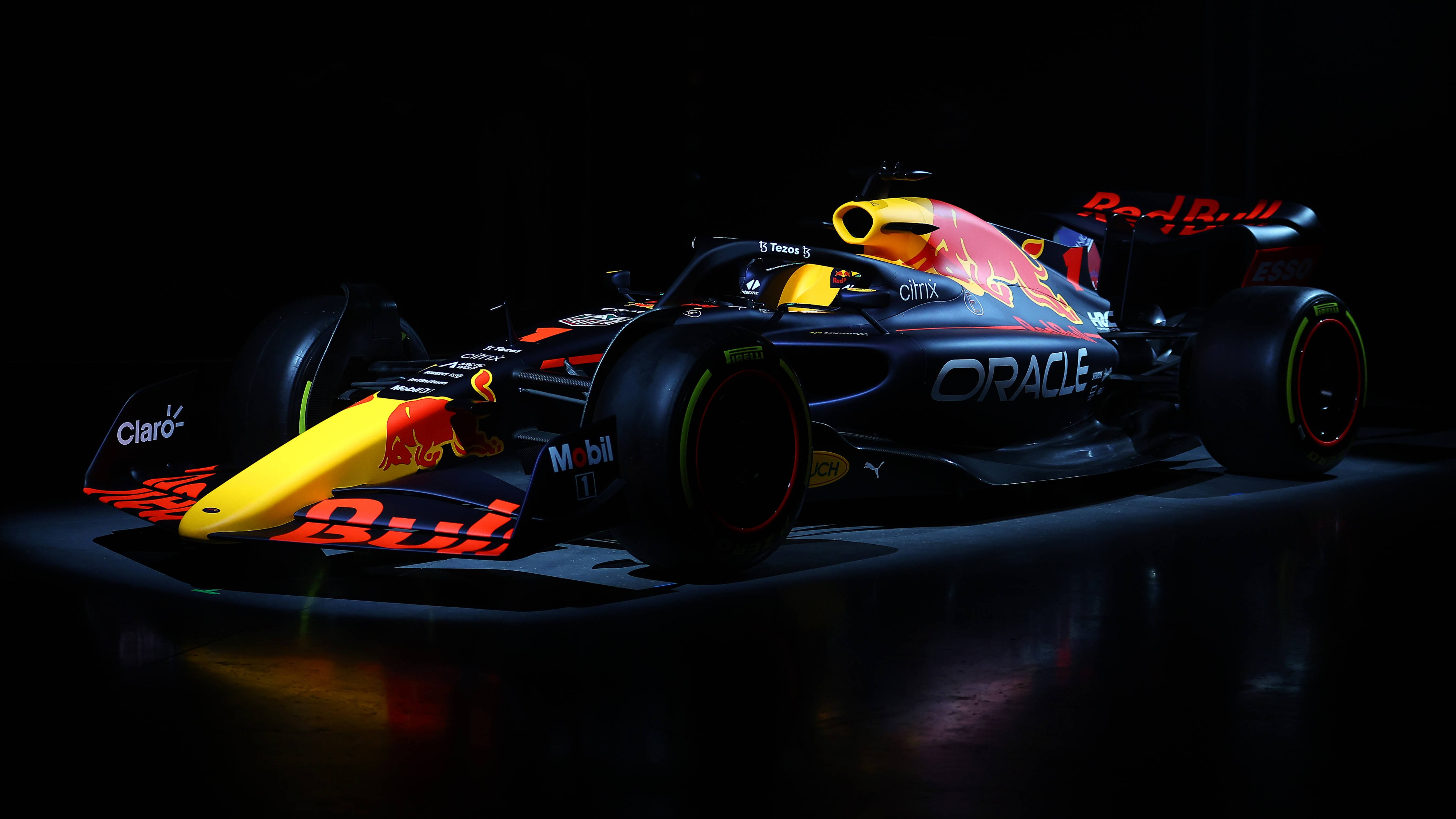 Racing Car 桌布 壁紙 — 一架線條流暢的Red Bull一級方程式賽車，帶有鮮豔的黃黑配色，在黑暗的攝影棚背景下被戲劇性地照亮。