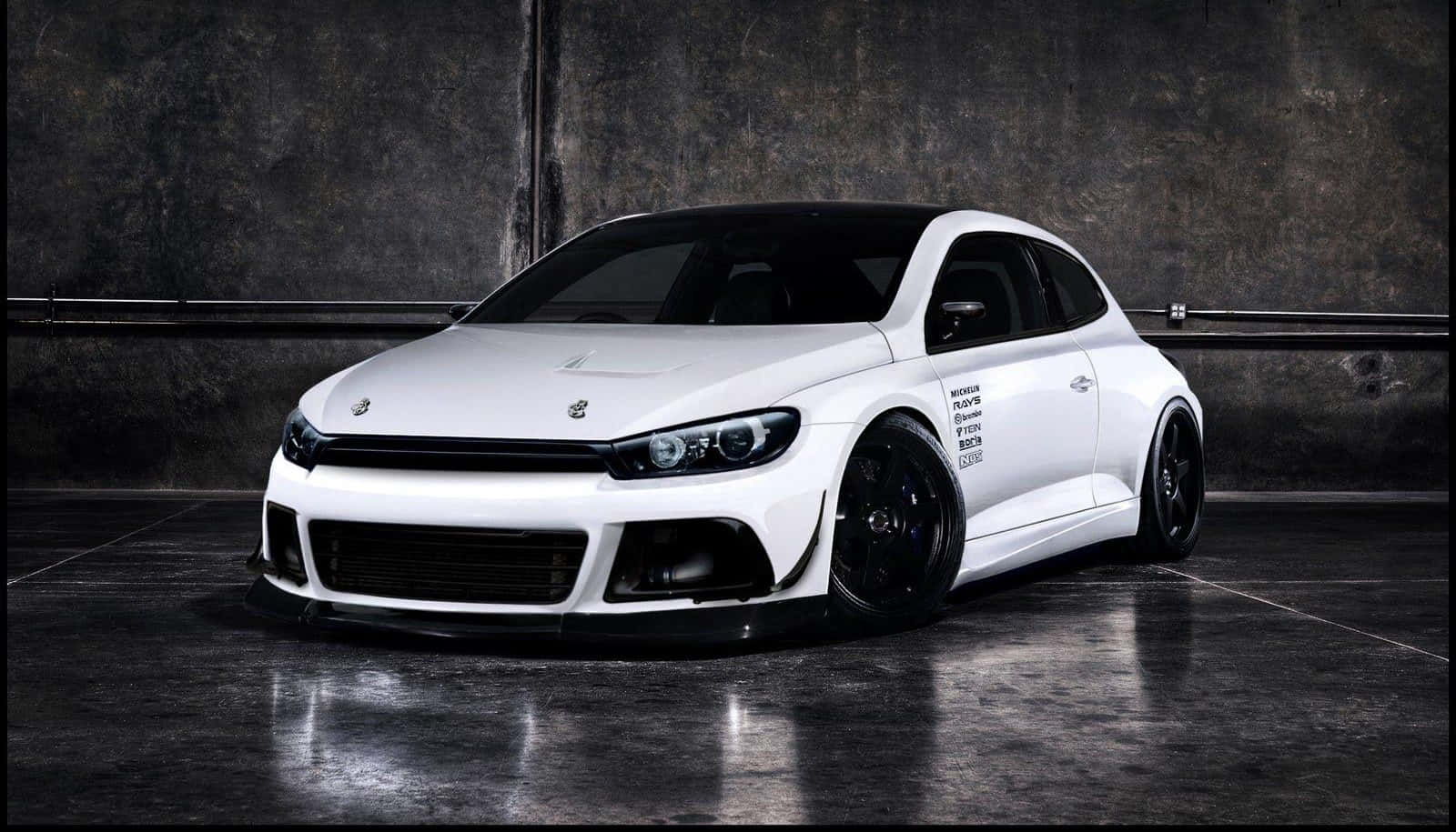 Tuned Car 桌布 壁紙 — 一架線條流暢的白色改裝福士Scirocco，帶有黑色飾件和訂製輪圈，停泊在光線昏暗、混凝土地面反光的工業車庫內。