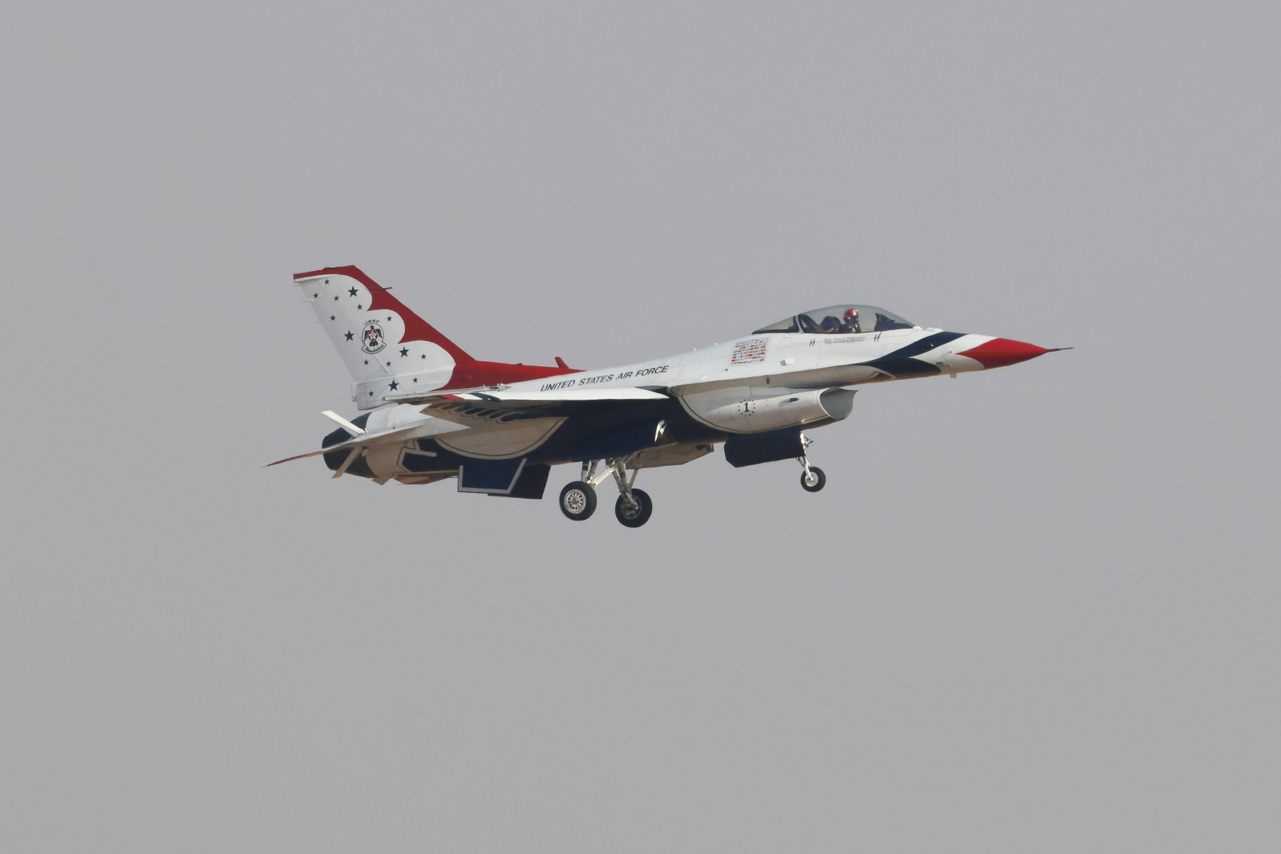 Plane 桌布 壁紙 — 一架美國空軍雷鳥戰鬥機以愛國塗裝在低空飛行時，在柔和的灰色天空下急劇傾斜。