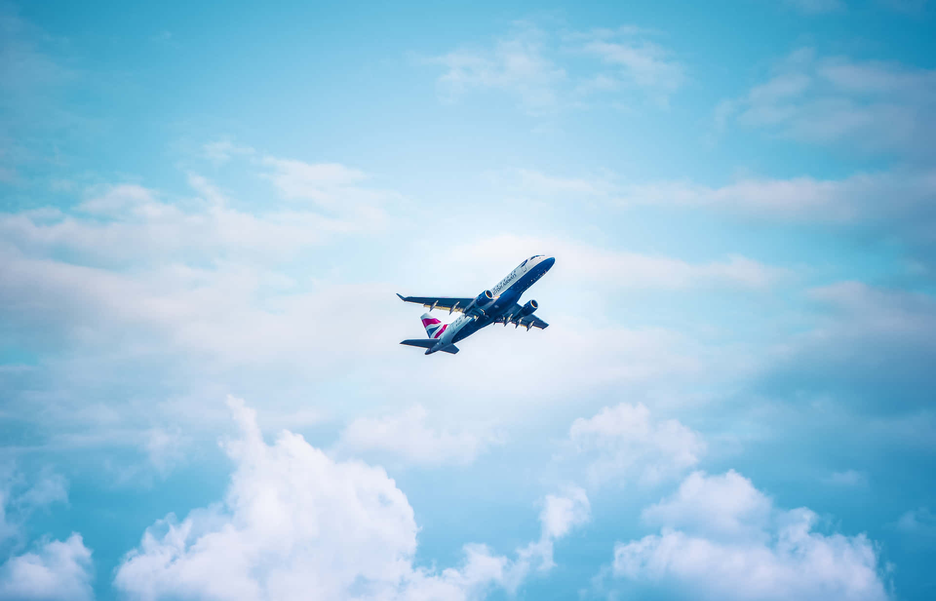  壁紙 — 一架英國航空公司的飛機在鮮豔的藍天背景下優雅地翱翔於蓬鬆的白雲之上。