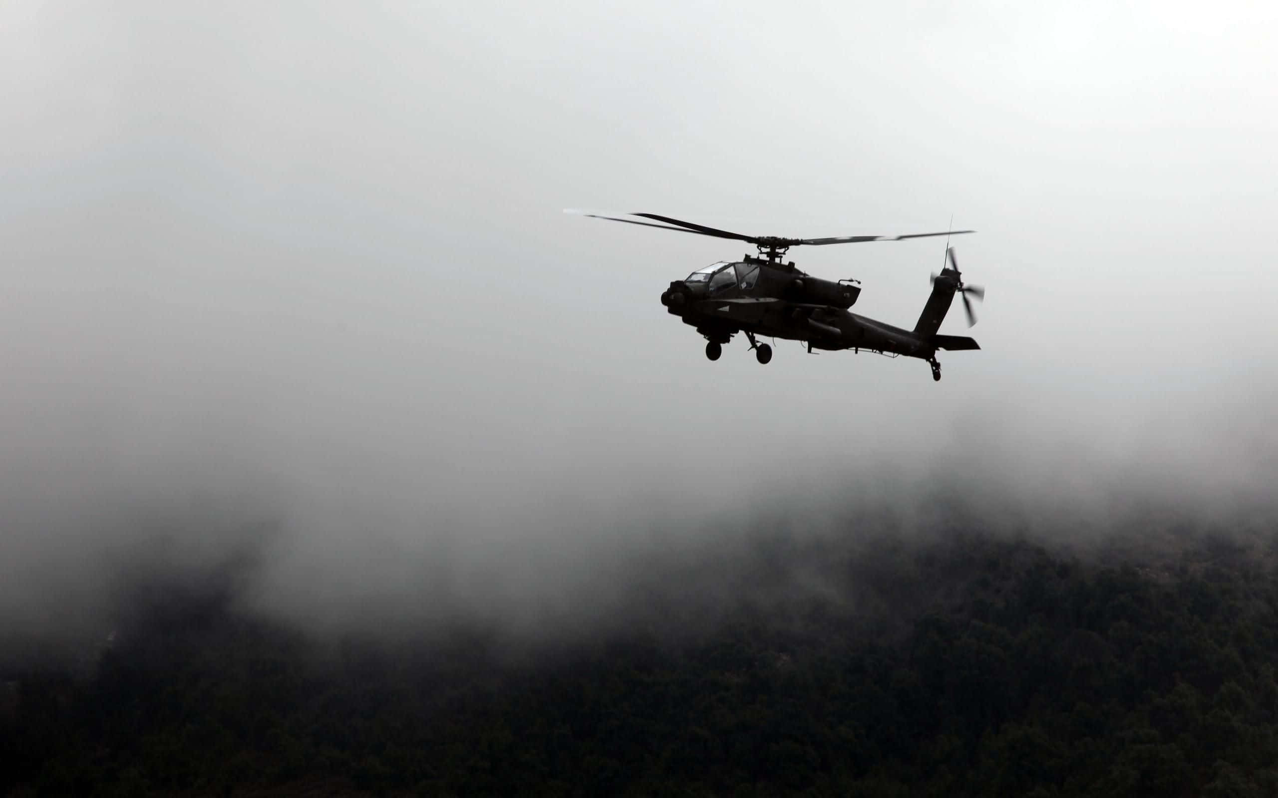 Helicopter 桌布 壁紙 — 一架軍用直升機在單色調的森林景觀上空穿過濃霧飛行。