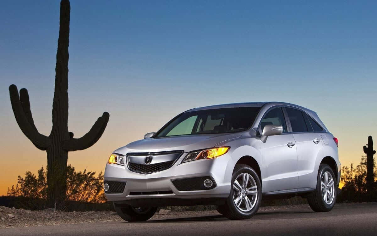 Acura Rdx 桌布 壁紙 — 一架銀色Acura SUV在日落時停泊在沙漠公路旁，旁邊有一棵高大的薩瓜羅仙人掌。
