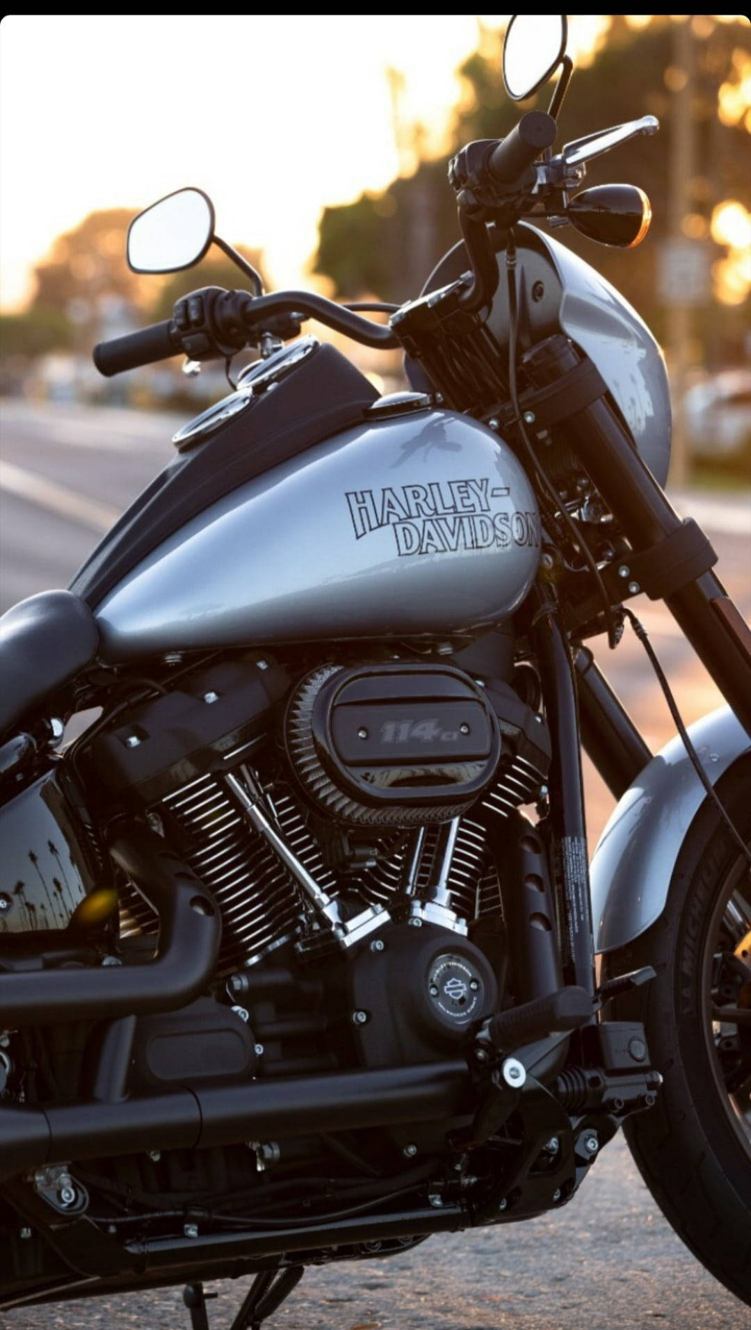 哈雷戴維森 桌布 壁紙 — 一架銀色Harley-Davidson電單車在金色夕陽下閃耀，帶有鉻合金細節和黑色點綴。