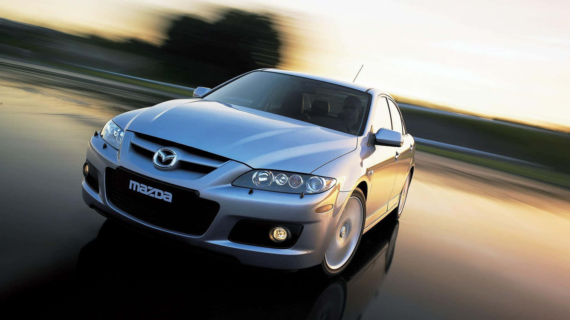 Mazda 6 桌布 壁紙 — 一架銀色Mazda房車在黃金時刻沿濕滑道路疾馳，背景帶有動態模糊效果。
