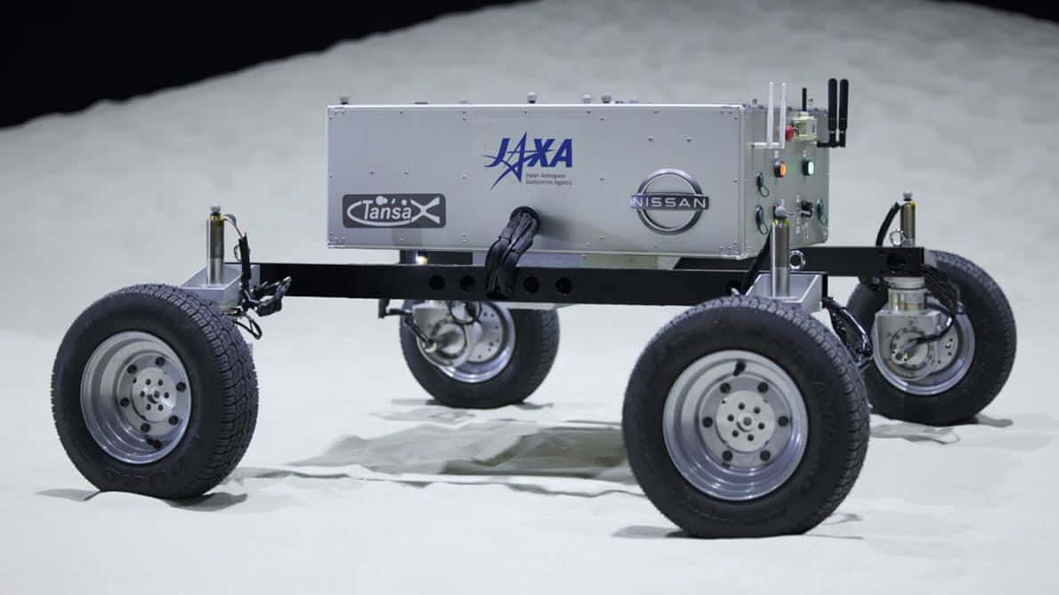 Lunar Rover 桌布 壁紙 — 一架銀色NASA JAXA日產月球車配備堅固輪胎，在工作室燈光下停放在模擬月球表面。