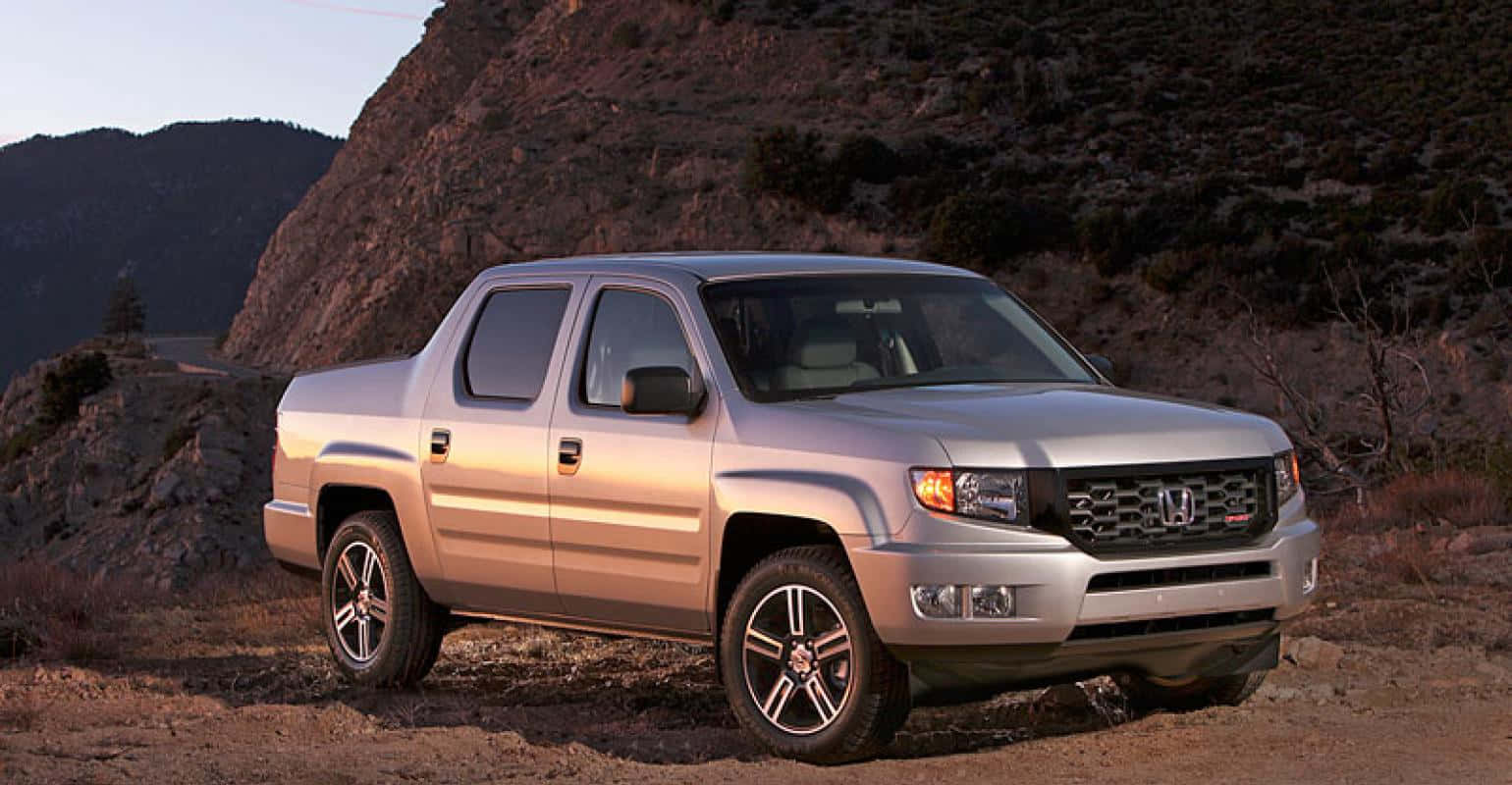 Honda Ridgeline 桌布 壁紙 — 一架銀色本田 Ridgeline 輕型貨車停泊在日落時分岩石山坡旁的泥路上。