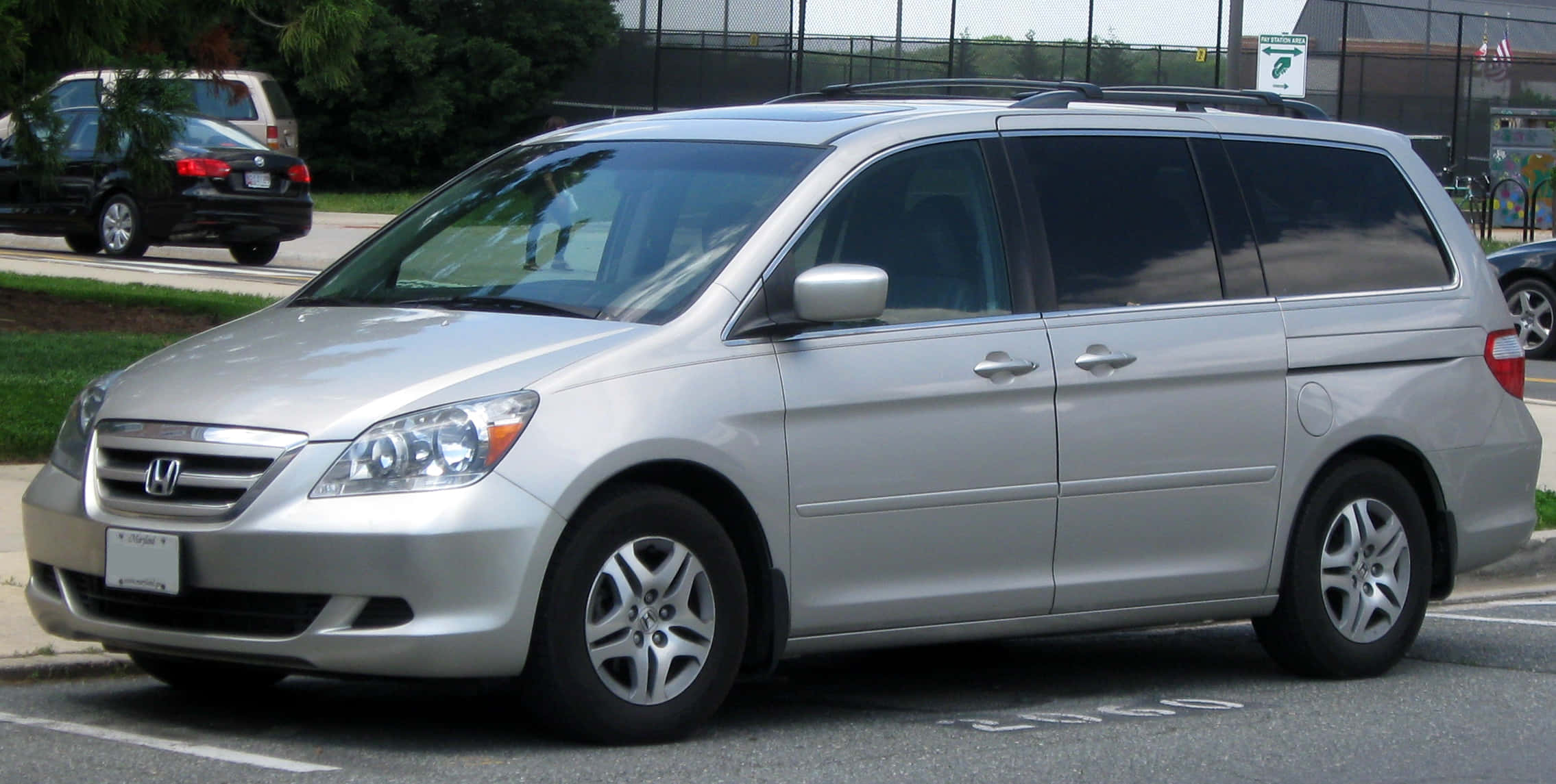 Honda Odyssey 桌布 壁紙 — 一架銀色本田Odyssey小型貨車停泊在一個有樹木和圍欄的停車場中。
