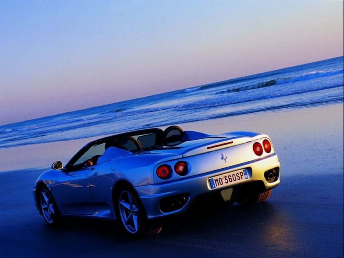 Ferrari 360 Modena 桌布 壁紙 — 一架銀色法拉利360 Spider在暮色中停泊在濕漉漉的沙灘上，海浪在柔和的藍天下翻滾。