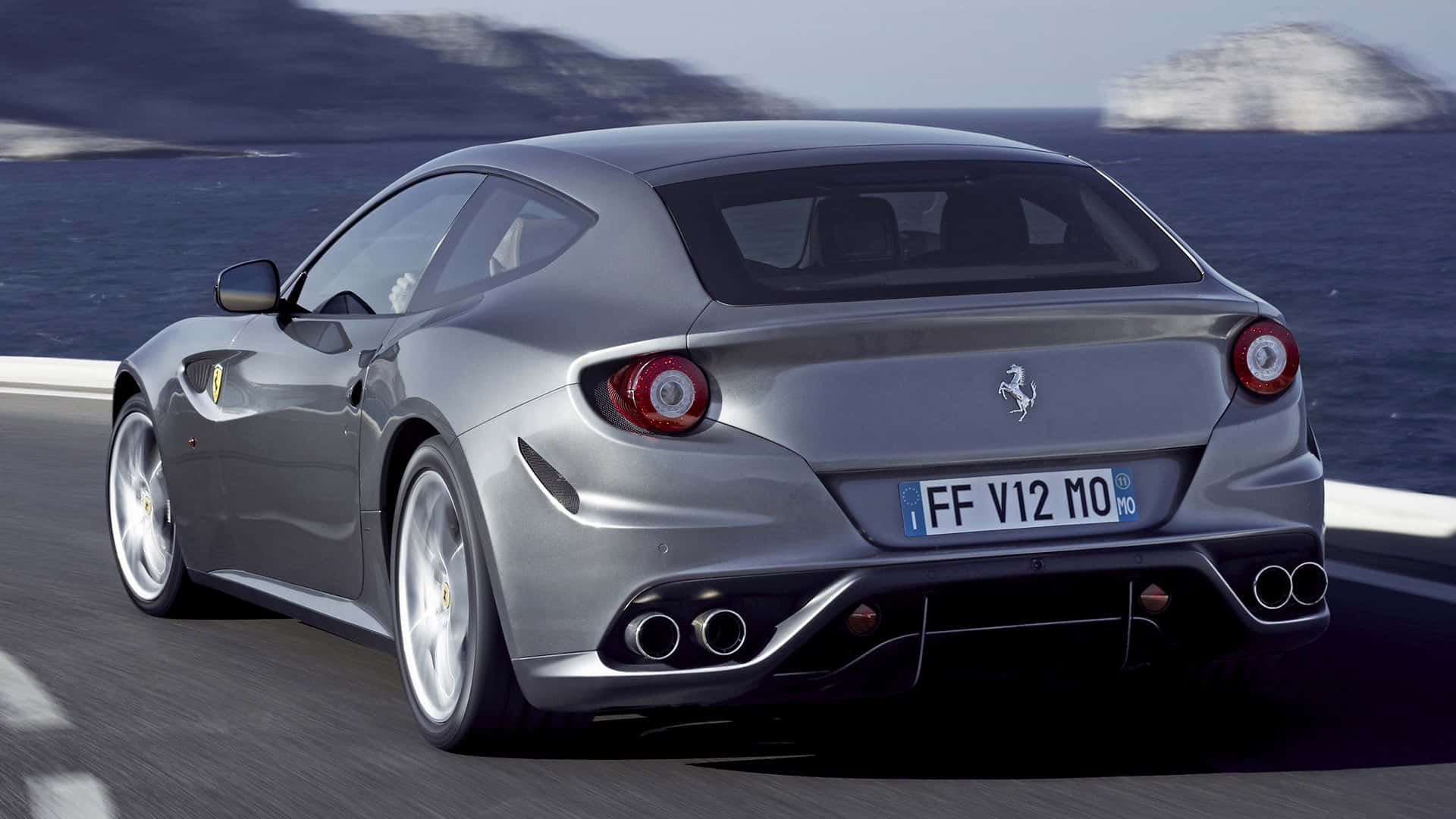 Ferrari Ff 桌布 壁紙 — 一架銀色法拉利FF沿著海岸公路疾馳，背景係海洋同懸崖。