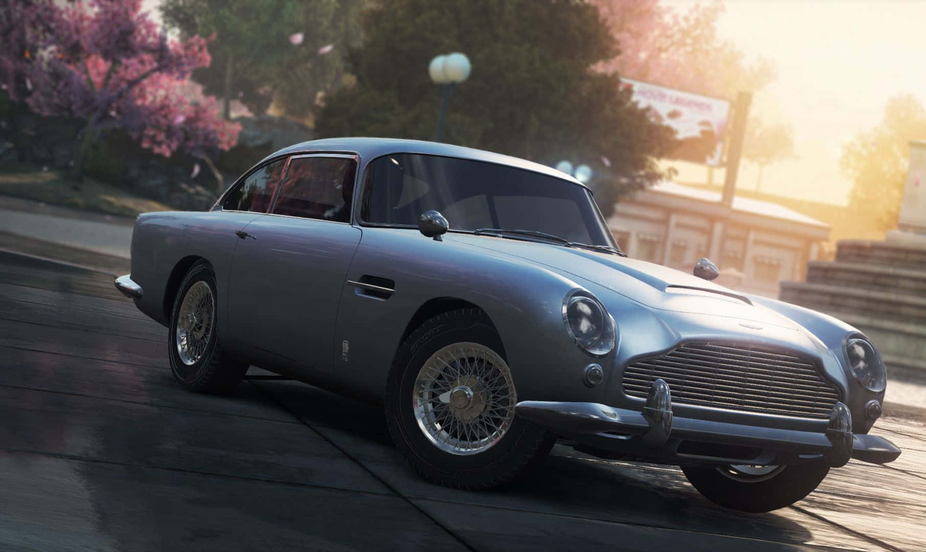 Aston Martin Db5 桌布 壁紙 — 一架銀色流線型Aston Martin DB5在陽光明媚、兩旁開滿粉紅色櫻花的街道上滑行。