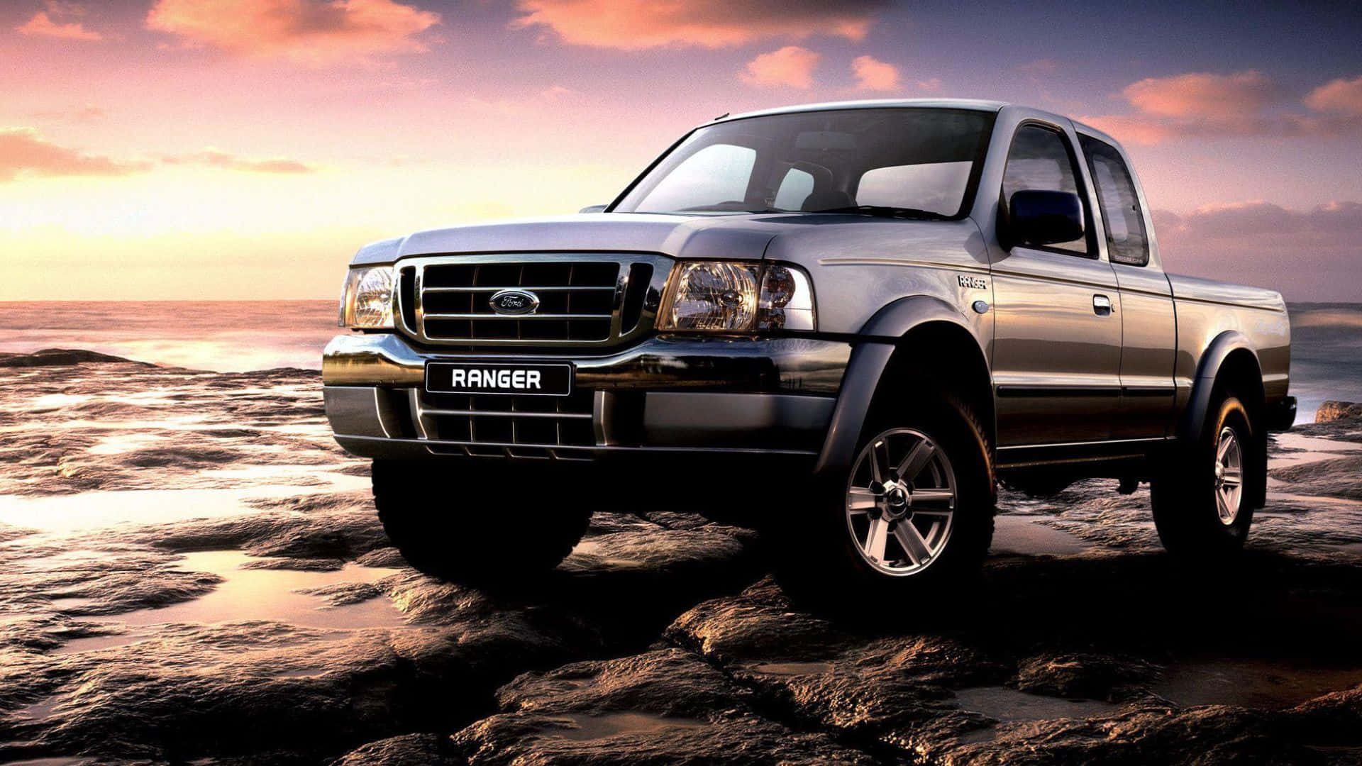 Ford Ranger 桌布 壁紙 — 一架銀色福特Ranger皮卡車在日落時分大膽地停在濕岩石上，身後海浪拍打。