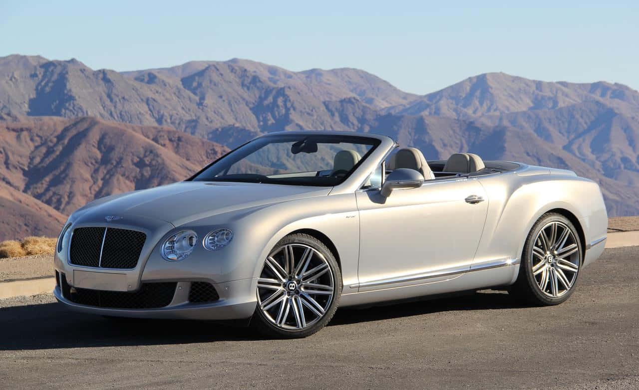 Convertible 桌布 壁紙 — 一架銀色賓利開篷車停泊在沙漠公路上，背景是崎嶇的山脈，天空清澈湛藍。
