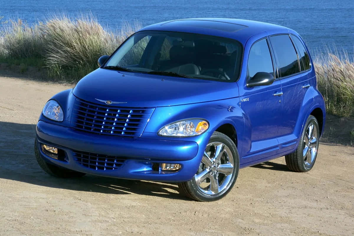 Chrysler Pt Cruiser 桌布 壁紙 — 一架閃亮的藍色PT Cruiser停泊在沙灘上，背景是海洋和沙丘草。