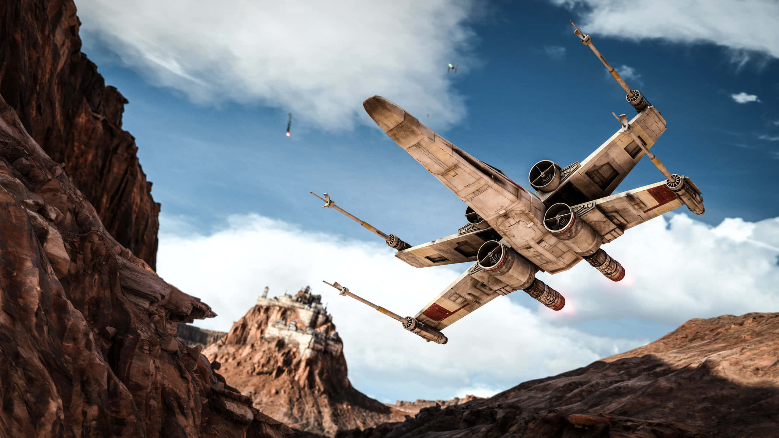 X-wing Fighter 桌布 壁紙 — 一架風化的X翼戰機在晴朗藍天和零星白雲下飛越峽谷。
