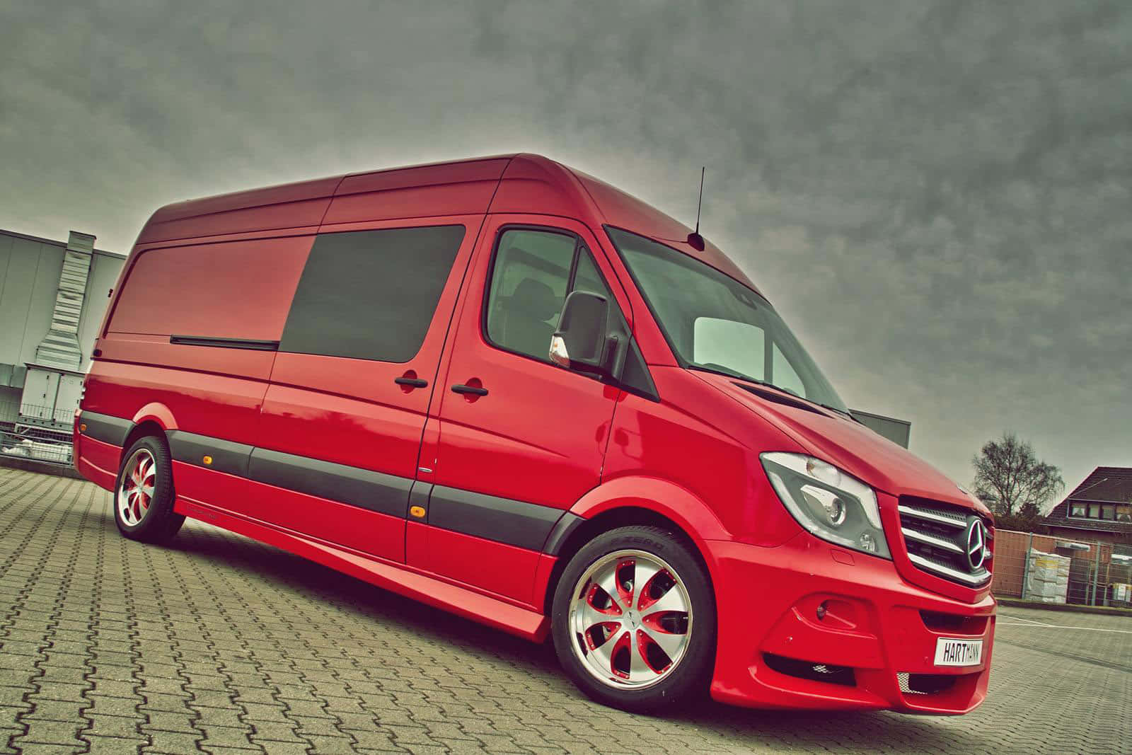 Mercedes Benz Sprinter 桌布 壁紙 — 一架鮮紅色嘅Mercedes-Benz Sprinter客貨車，配備定制合金輪圈，停泊喺鋪砌嘅停車場，天空多雲。