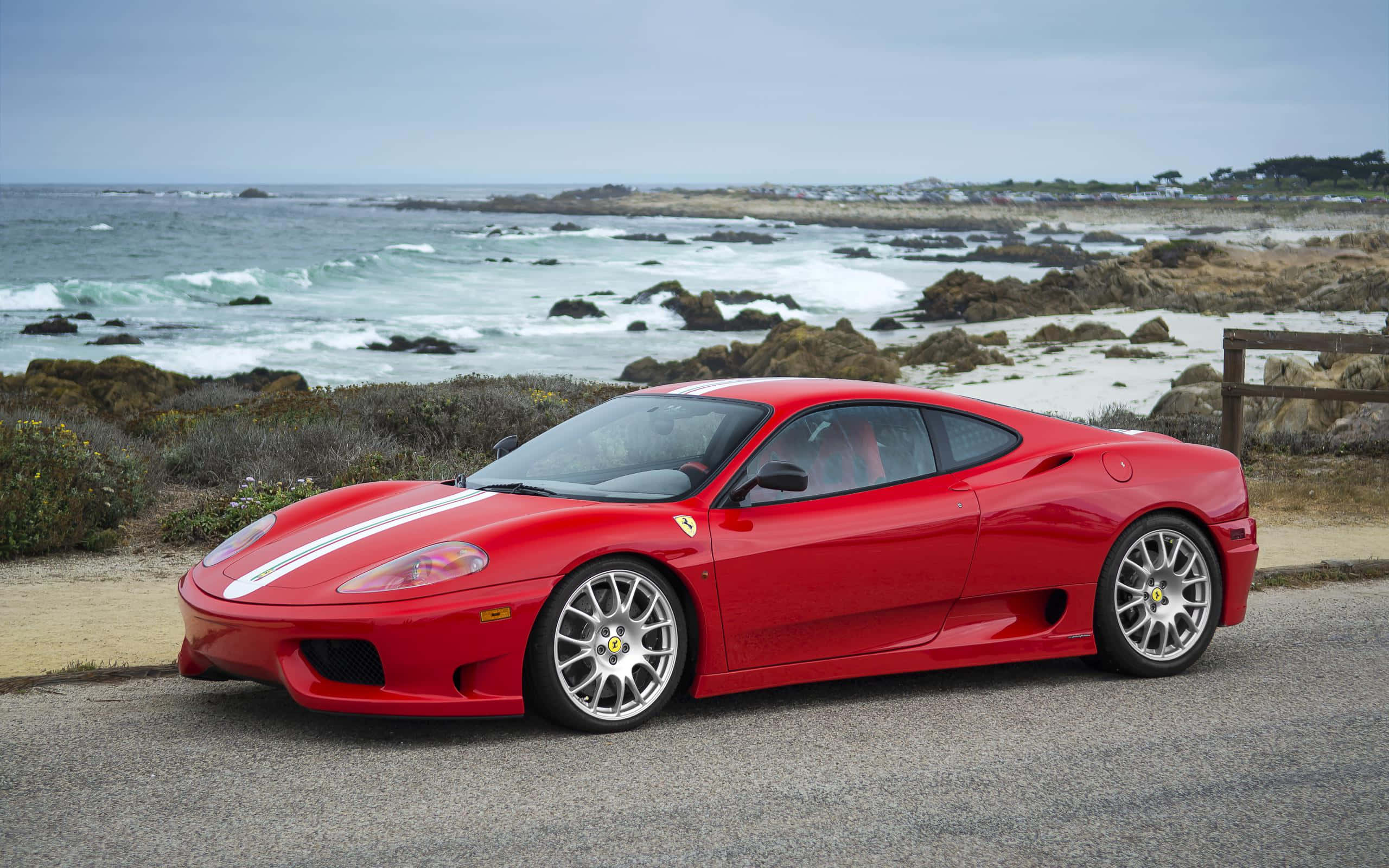 Ferrari 360 Modena 桌布 壁紙 — 一架鮮紅色法拉利F430跑車停泊在海濱公路上，背景是翻騰的海浪和岩石海岸。
