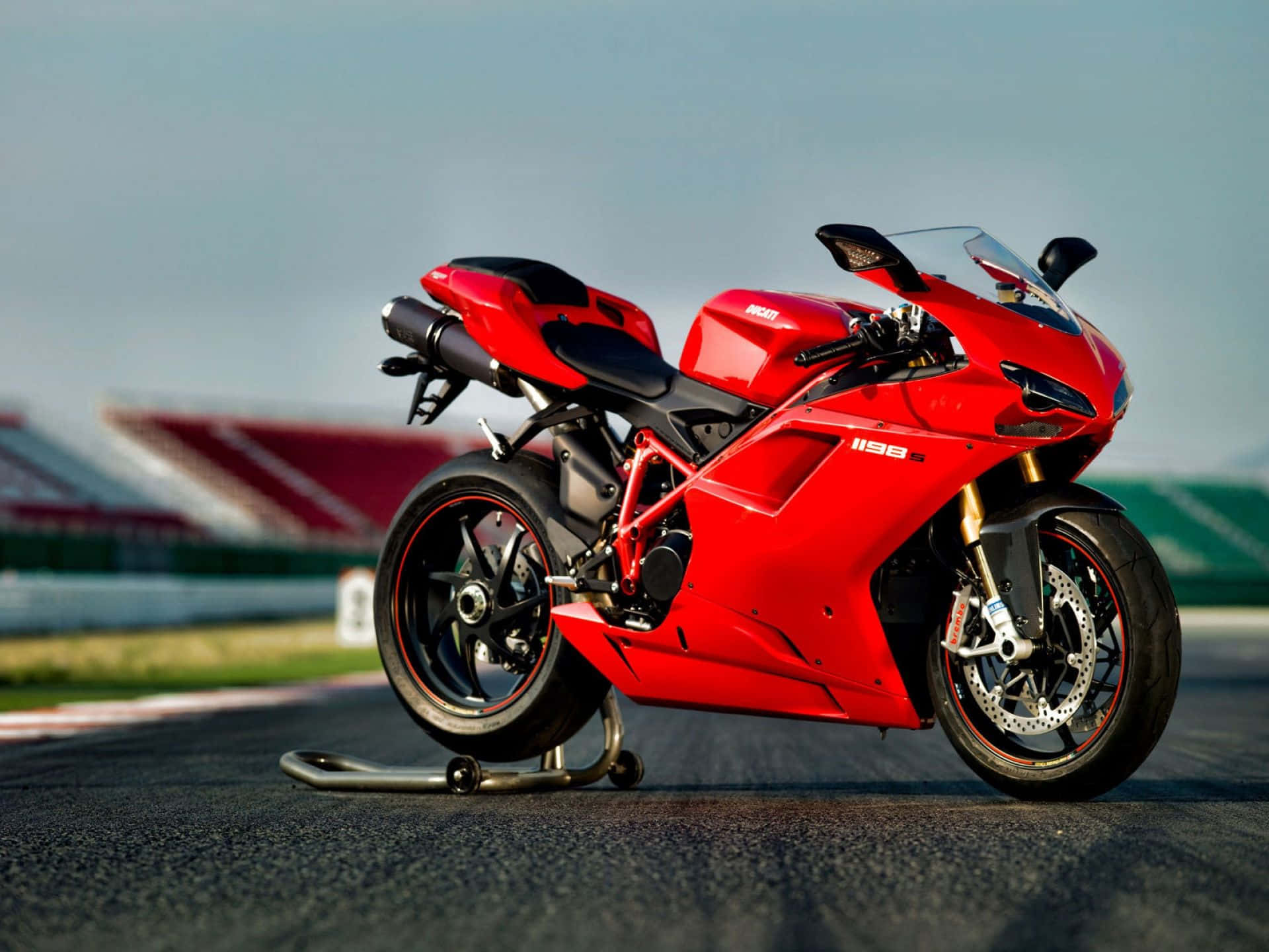 機車 桌布 壁紙 — 一架鮮紅色的Ducati 1198電單車在賽道上蓄勢待發，背景是模糊的看台。